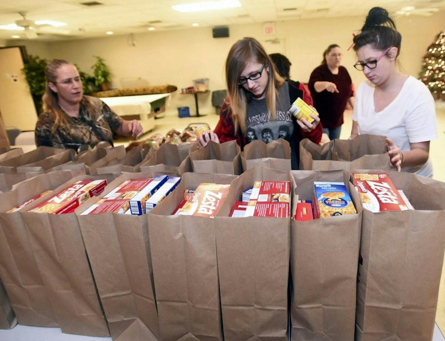 In this photo taken on Dec. 10, 2014, from left, Billie Tice, Brittany, and Amber Breneman help other volunteers make food donation bags at VFW Post 41 in Chambersburg, Pa. (AP Photo/Public Opinion, Ryan Blackwell) HERALD-MAIL OUT; THE RECORD HERALD OUT