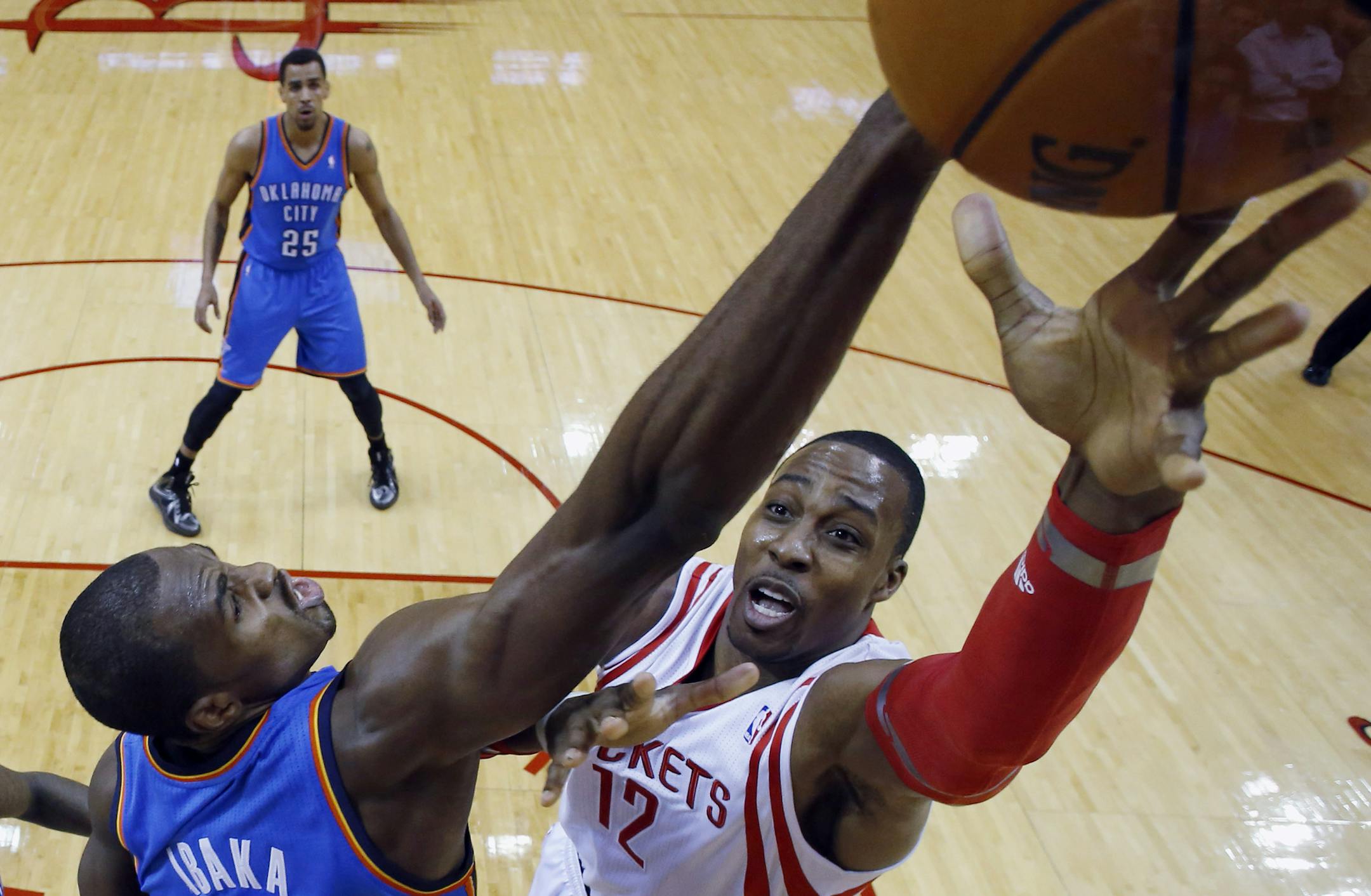 Houston Rockets' Dwight Howard (12) shoots as Oklahoma City Thunder's Serge Ibaka (9) defends during the first quarter of an NBA basketball game, Thursday, Jan. 16, 2014, in Houston. (AP Photo/David J. Phillip)