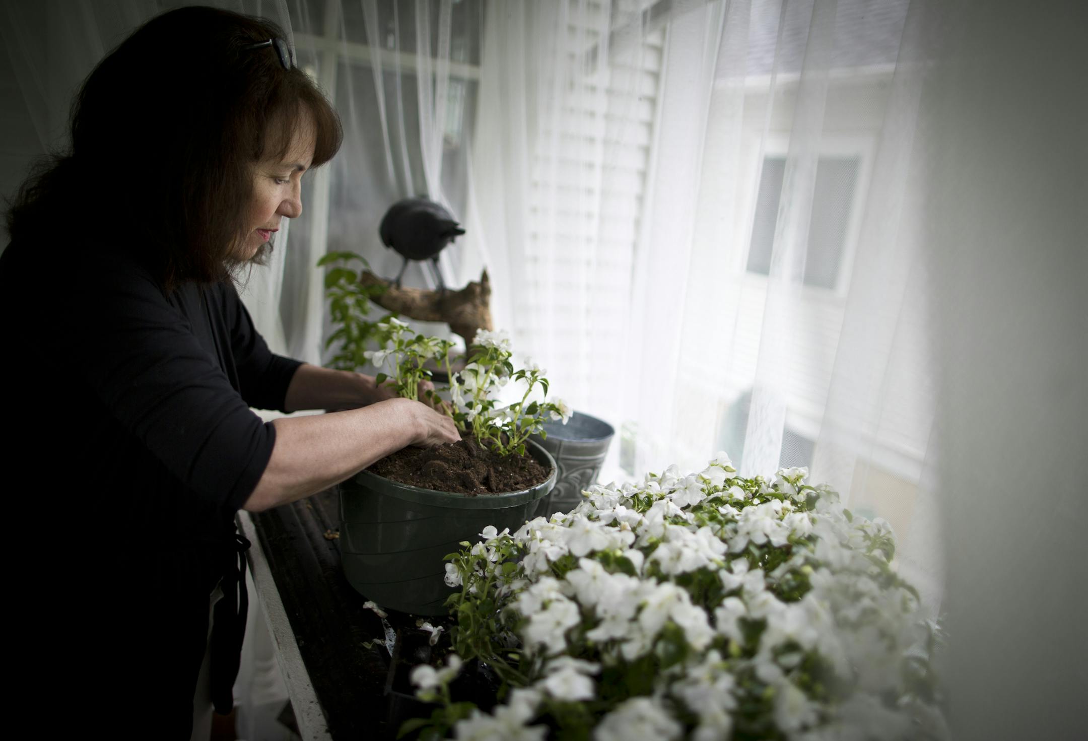 Jeanne Long made new hanging baskets on her front porch where last week several of similar hanging baskets were stolen. This is not the first time plants have been stolen from her home. She has replaced a few and wired them tightly to the porch. She was photographed at home in Minneapolis, Minn., June 12, 2013.] (RENEE JONES SCHNEIDER * reneejones@startribune.com)