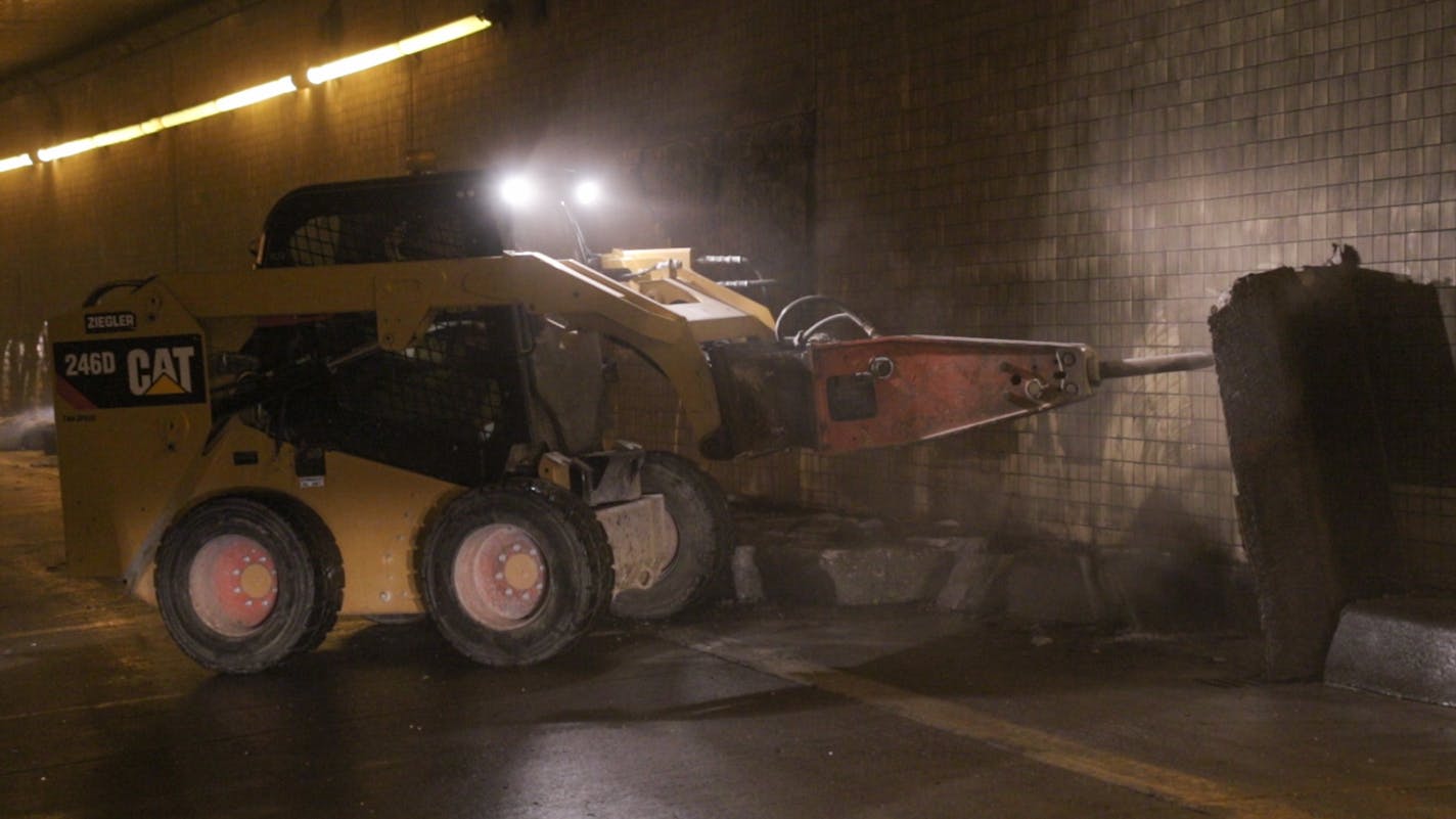 Workers use a large jackhammer to destroy the curbs on either side of the Lowry Hill Tunnel to make enough room for another lane. It's powerful enough to make quick work of the curbs, much to the surprise of MnDOT resident engineer Steve Barrett Photo By: Matt Weber