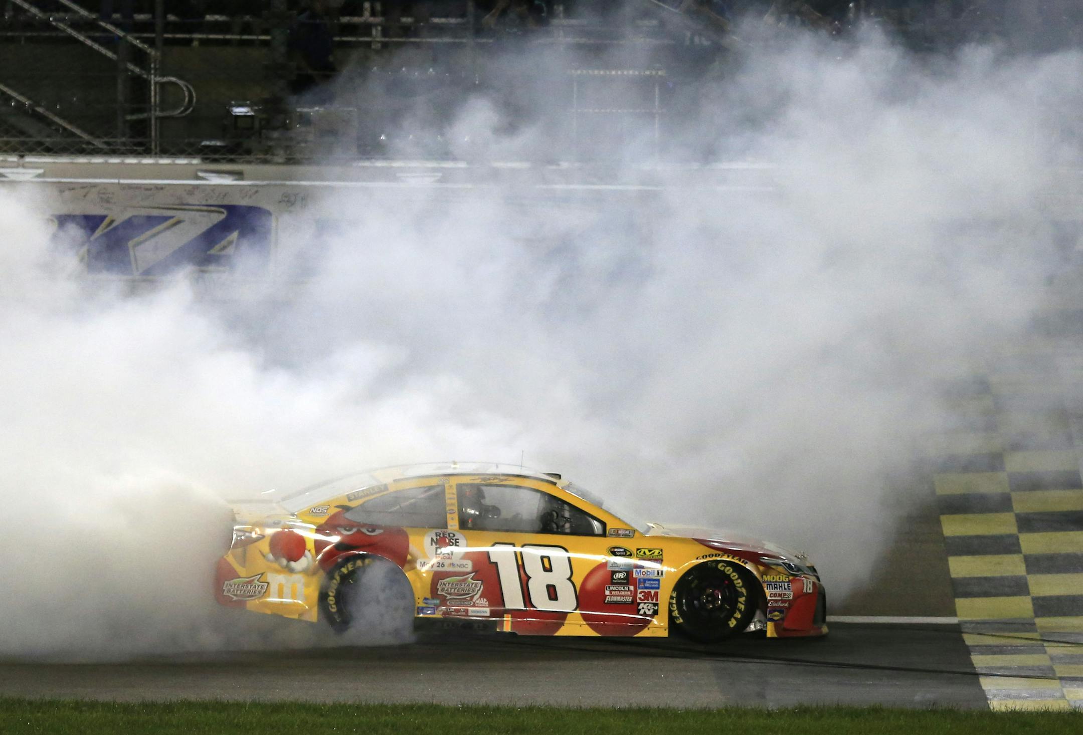 Kyle Busch (18) celebrates after winning a NASCAR Sprint Cup Series auto race at Kansas Speedway in Kansas City, Kan., Saturday, May 7, 2016. (AP Photo/Orlin Wagner)