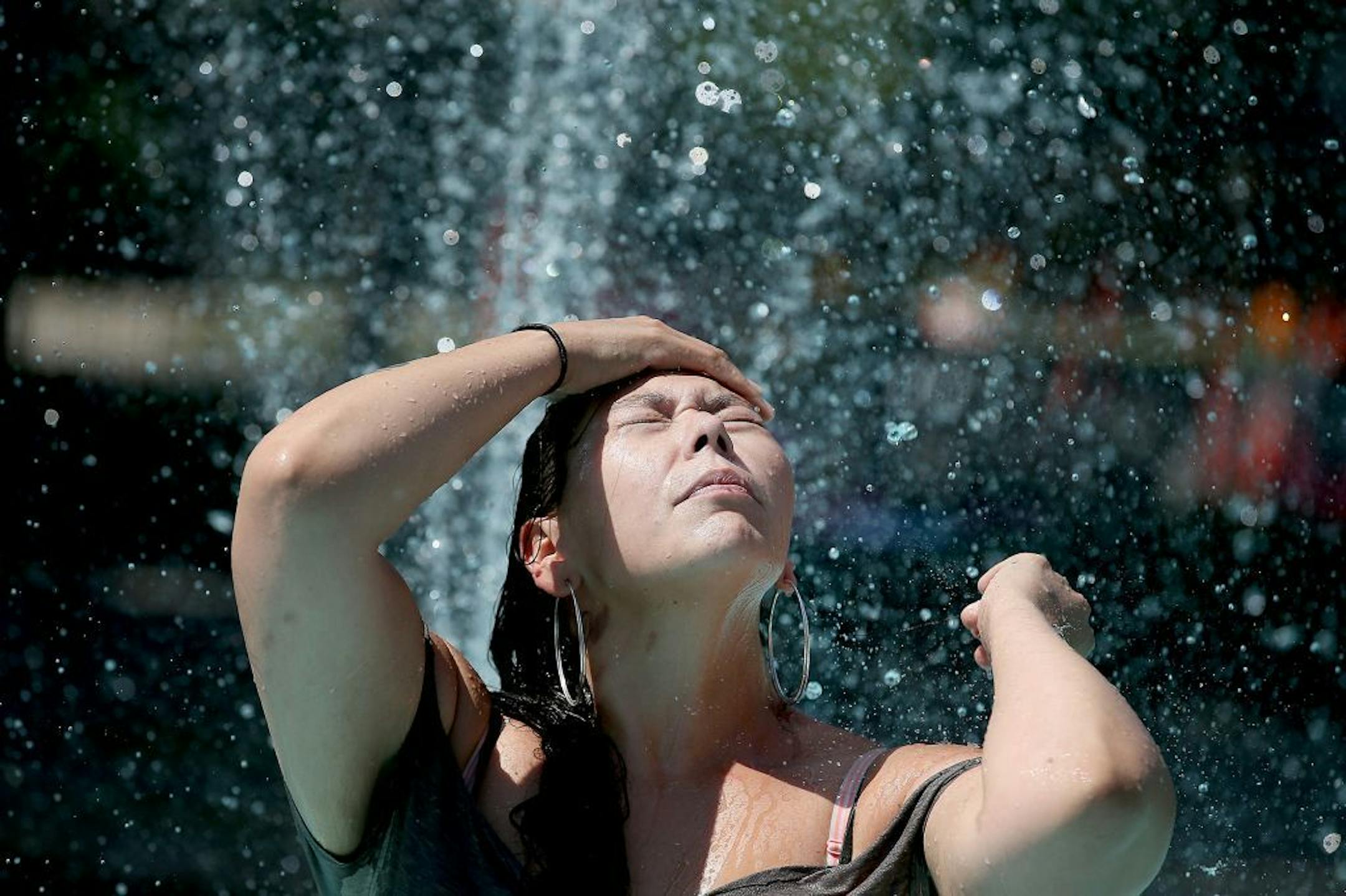 Heather LeClaire of Minneapolis took a break from her walk to cool off in a wading pool at Central Gym Park on Friday in Minneapolis.