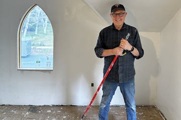 The man who led the effort to renovate a vacant house stands next to a pail of paint he was using on the walls.