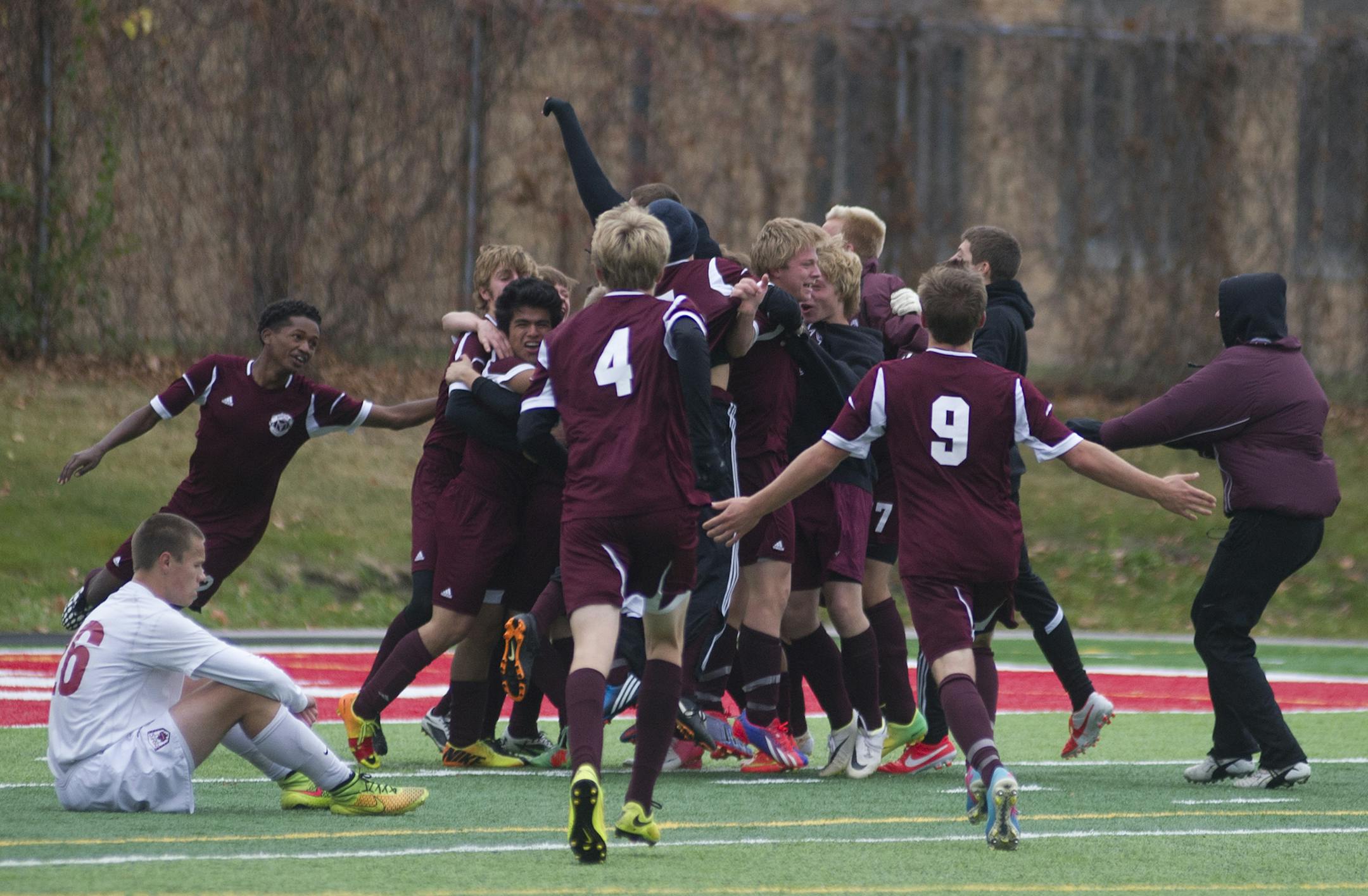 Maple Grove's Carson Thomas sits in disbelif as the Anoka boys soccer team rushes the field after Felipe Genchi scored a game winning goal in the second ten minute period of overtime Tuesday, October 28, 2014 at Husky Stadium in St. Cloud, MN. Anoka now advances to the state finals. ] (Matthew Hintz, 102814, ST. Cloud)
