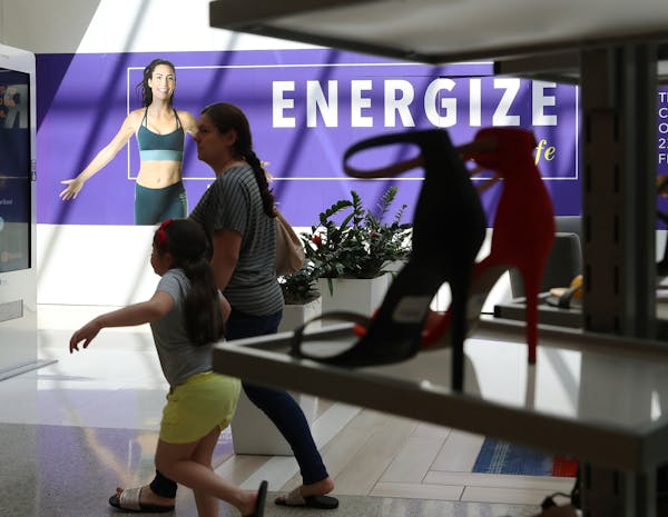 Shoppers walk past an advertisement for fitness-related businesses in the Yorktown Center shopping mall Tuesday, June 5, 2018, in Lombard. (John J. Ki