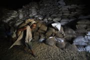 A laborer carries a sack of wheat in a state food corporation warehouse, in Jammu, India in 2011.