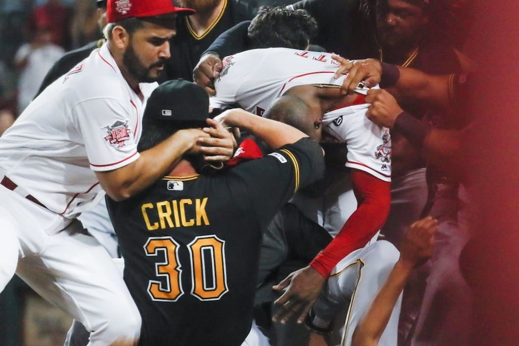 Pittsburgh Pirates' Kyle Crick (30) and Cincinnati Reds' Eugenio Suarez, left, and Amir Garrett, center right, brawl near the Pittsburgh dugout.