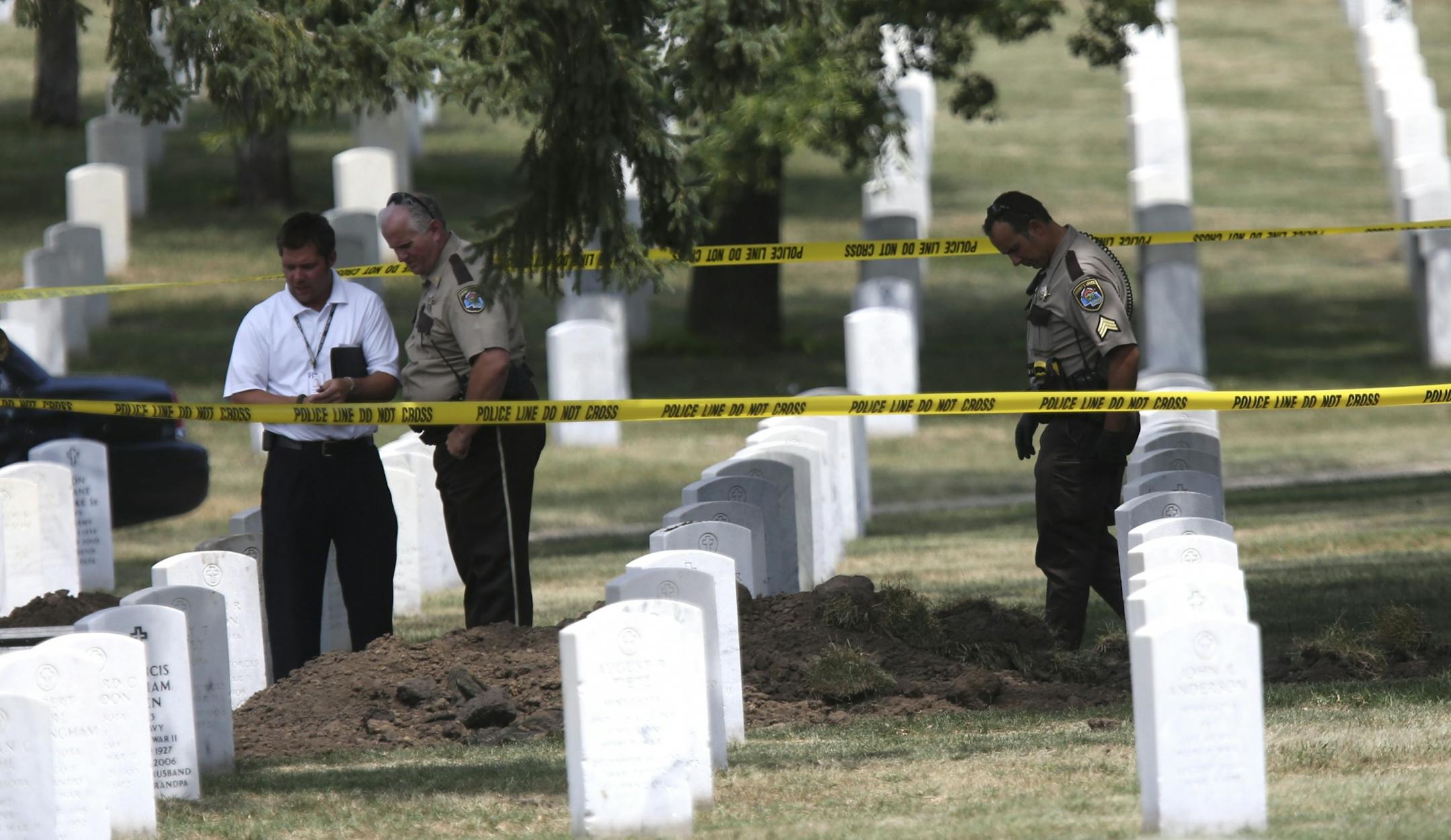 Investigators walked around the scene where a World War II veterans grave had been desecrated at Fort Snelling National Cemetery.