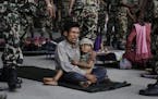 A man sits with a child on his lap as victims of Saturday&#xed;s earthquake, wait for ambulances after being evacuated at the airport in Kathmandu, Ne