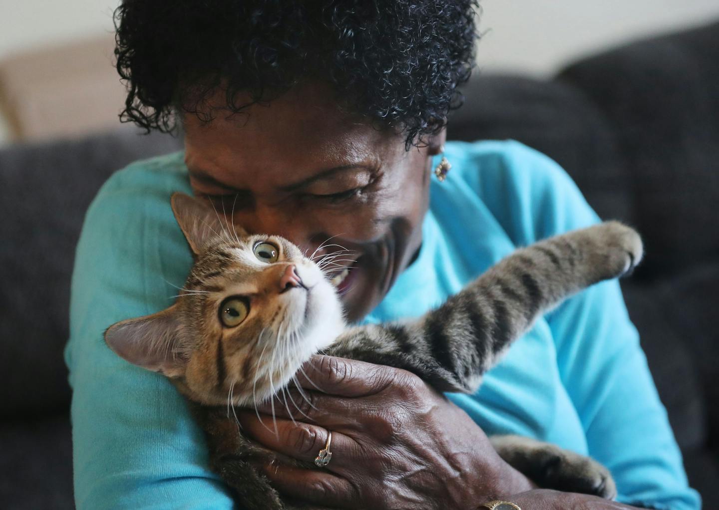 Diane of Minneapolis, who receives Ani-Meals on Wheels, with her cat Itty Bitty at her apartment after receiving a package for her pet to enjoy.