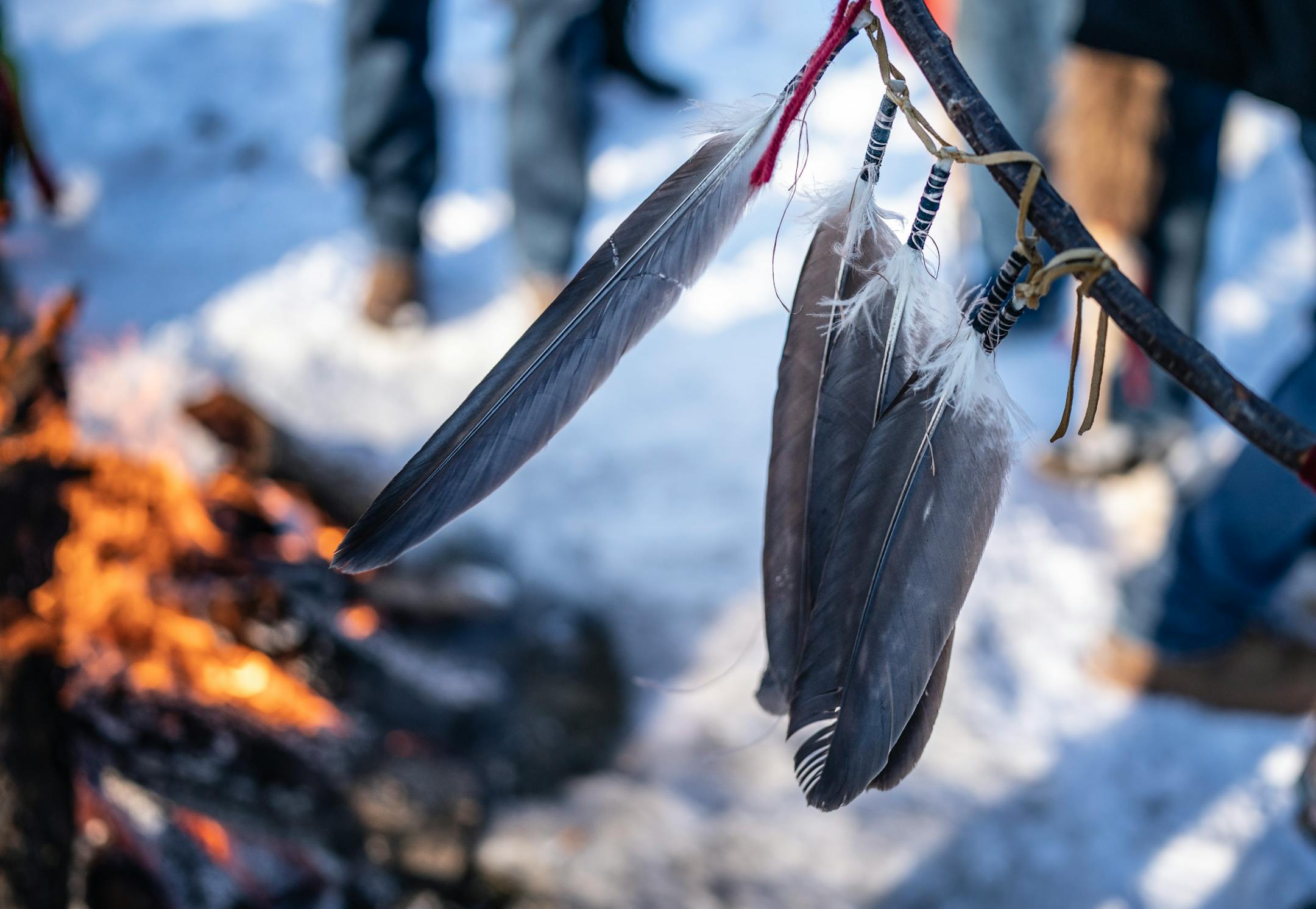 Feathers hung on a staff as people smudge at Memories Park before riding to Reconciliation Park in Mankato.