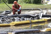 FILE - In this July 29, 2010, file photo, a worker monitors water in Talmadge Creek in Marshall Township, Mich., near the Kalamazoo River as oil from 