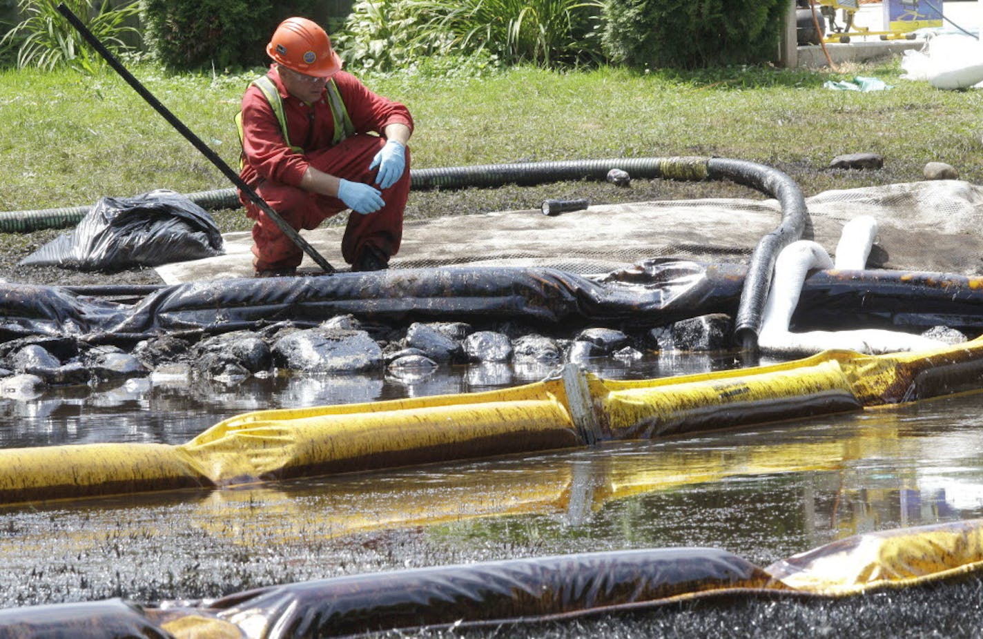 FILE - In this July 29, 2010, file photo, a worker monitors water in Talmadge Creek in Marshall Township, Mich., near the Kalamazoo River as oil from a ruptured pipeline, owned by Enbridge Inc., is attempted to be trapped by booms. Federal investigators are expected to present their findings Tuesday, July 10, 2012 on the likely cause of a pipeline rupture that spilled more than 800,000 gallons of crude oil into the river nearly two years ago. (AP Photo/Paul Sancya, File)