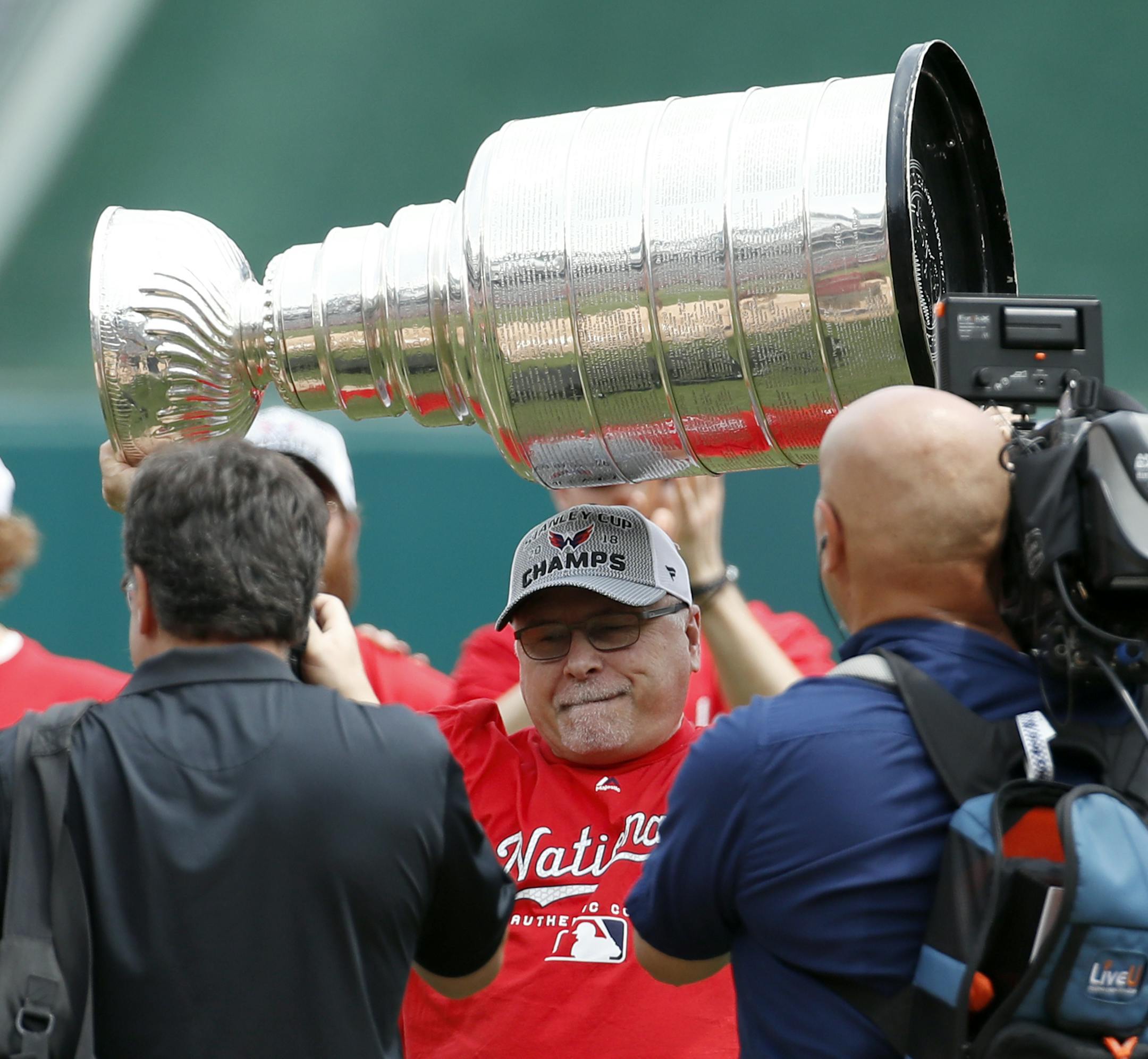 Washington Capitals head coach Barry Trotz lifts the Stanley Cup before a baseball game between the Washington Nationals and the San Francisco Giants at Nationals Park, Saturday, June 9, 2018, in Washington. (AP Photo/Alex Brandon) ORG XMIT: MIN2018061818395019