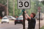Brooklyn Park police officer Todd Kanieski attataches a ribbon to a speed limit sign to remind drivers to drive safely this 4th of July weekend. -- Br