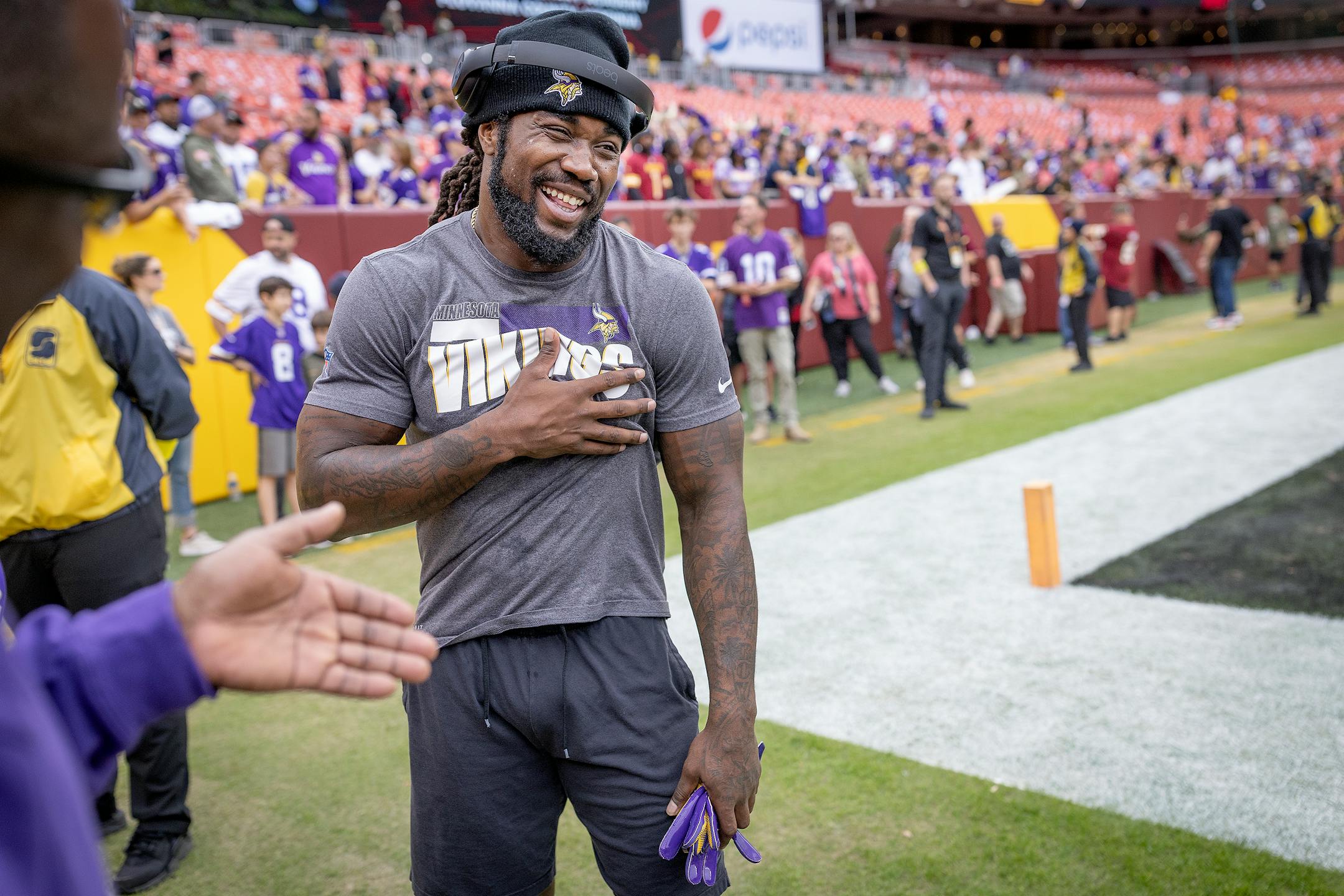 Minnesota Vikings running back Dalvin Cook shares a laugh with his parents on the field before the Vikings take on the Washington Commanders.