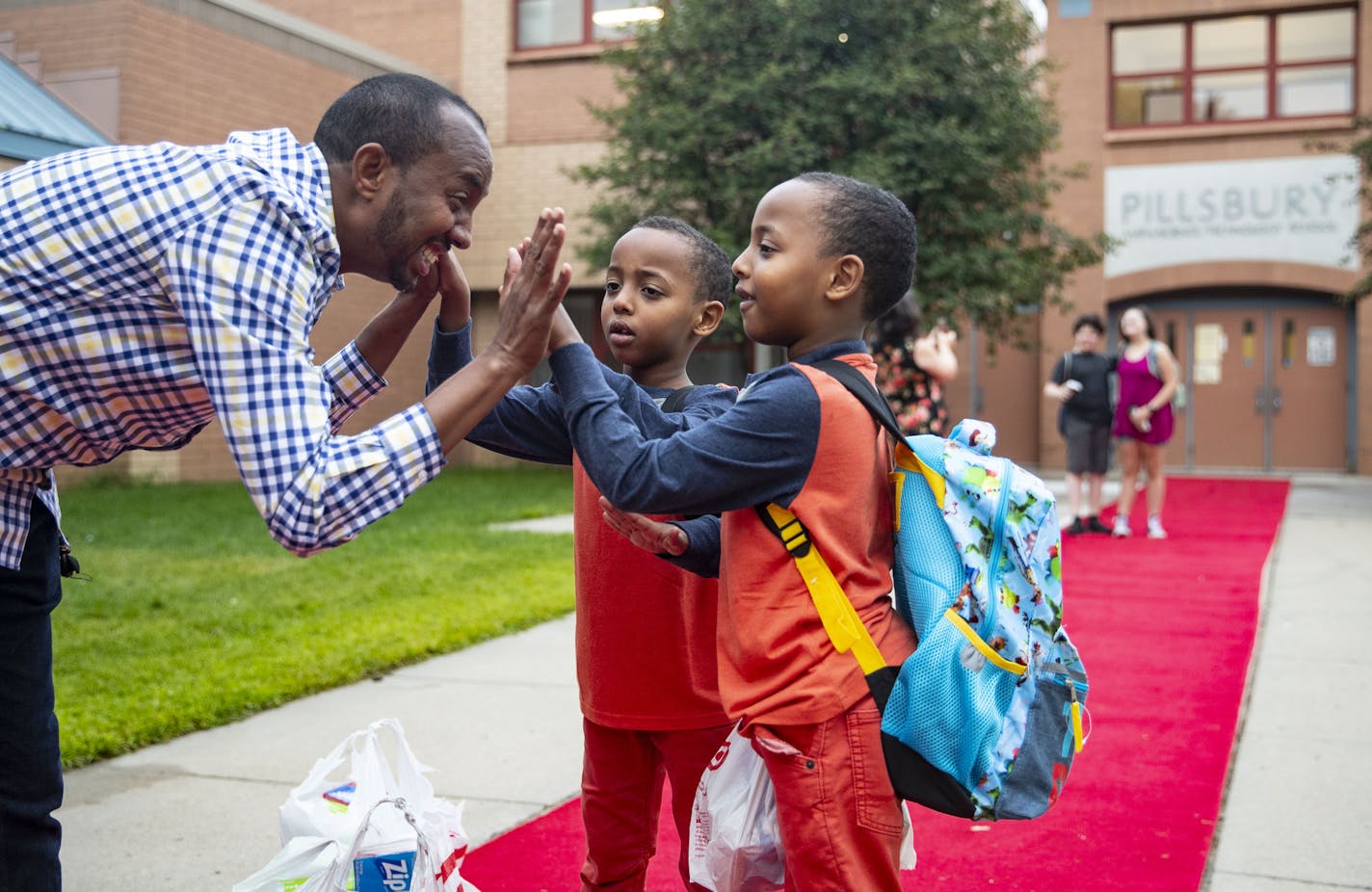 (From left) Abdirzak Alibos high-fived his twin sons, Rayan and Ridwan before they went in to start the second grade.]
ALEX KORMANN &#x2022; alex.kormann@startribune.com The Alibos family has six children who almost all attend Pillsbury Elementary School in Minneapolis, MN. On Tuesday September 3, 2019 school started in the Twin Cities and this group of kids headed out with their father, Abdirzak, to begin the school year.