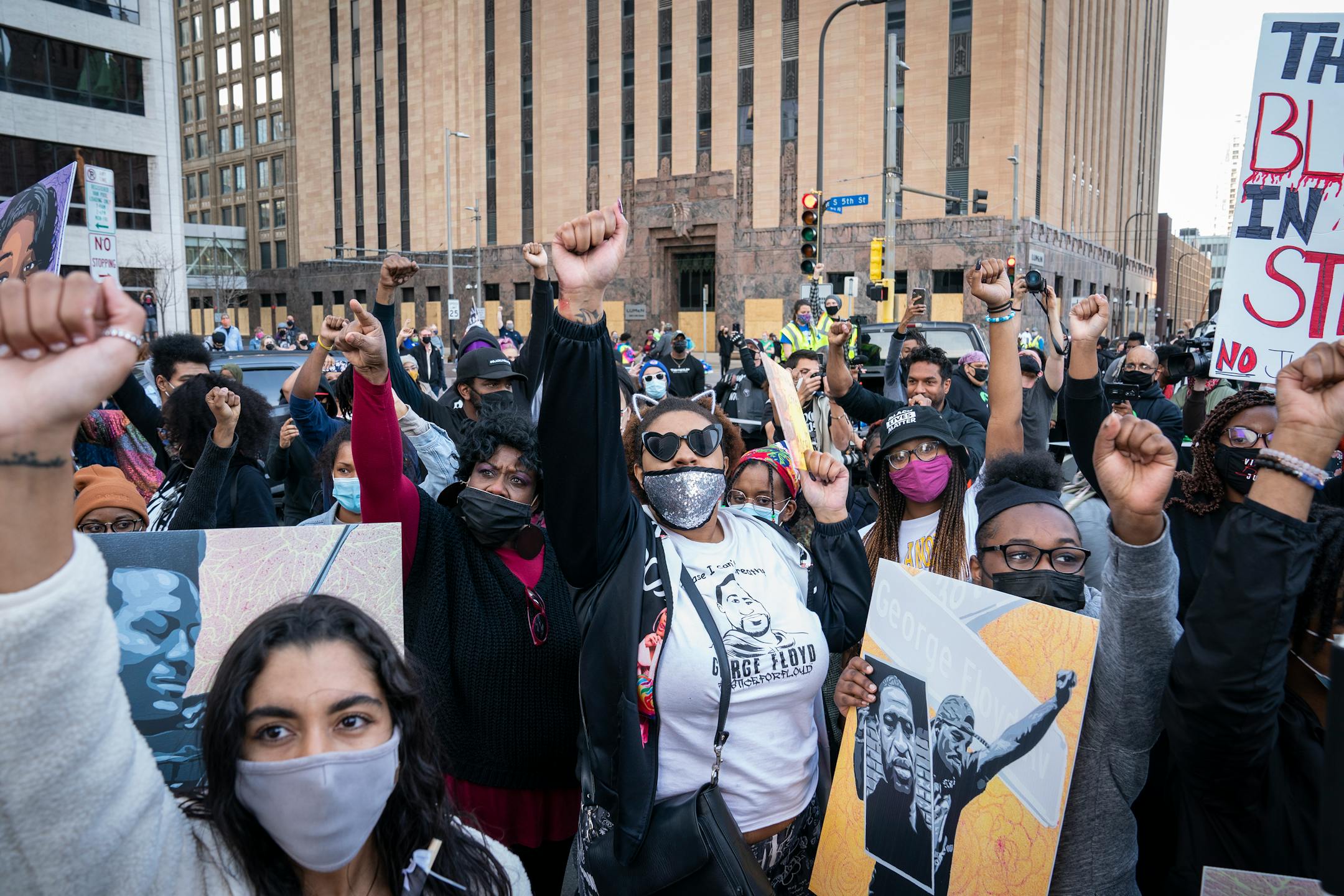 Protesters stood facing the Hennepin County Government Center with fists up during a rally and march on the first day of the Derek Chauvin murder trial in downtown Minneapolis.