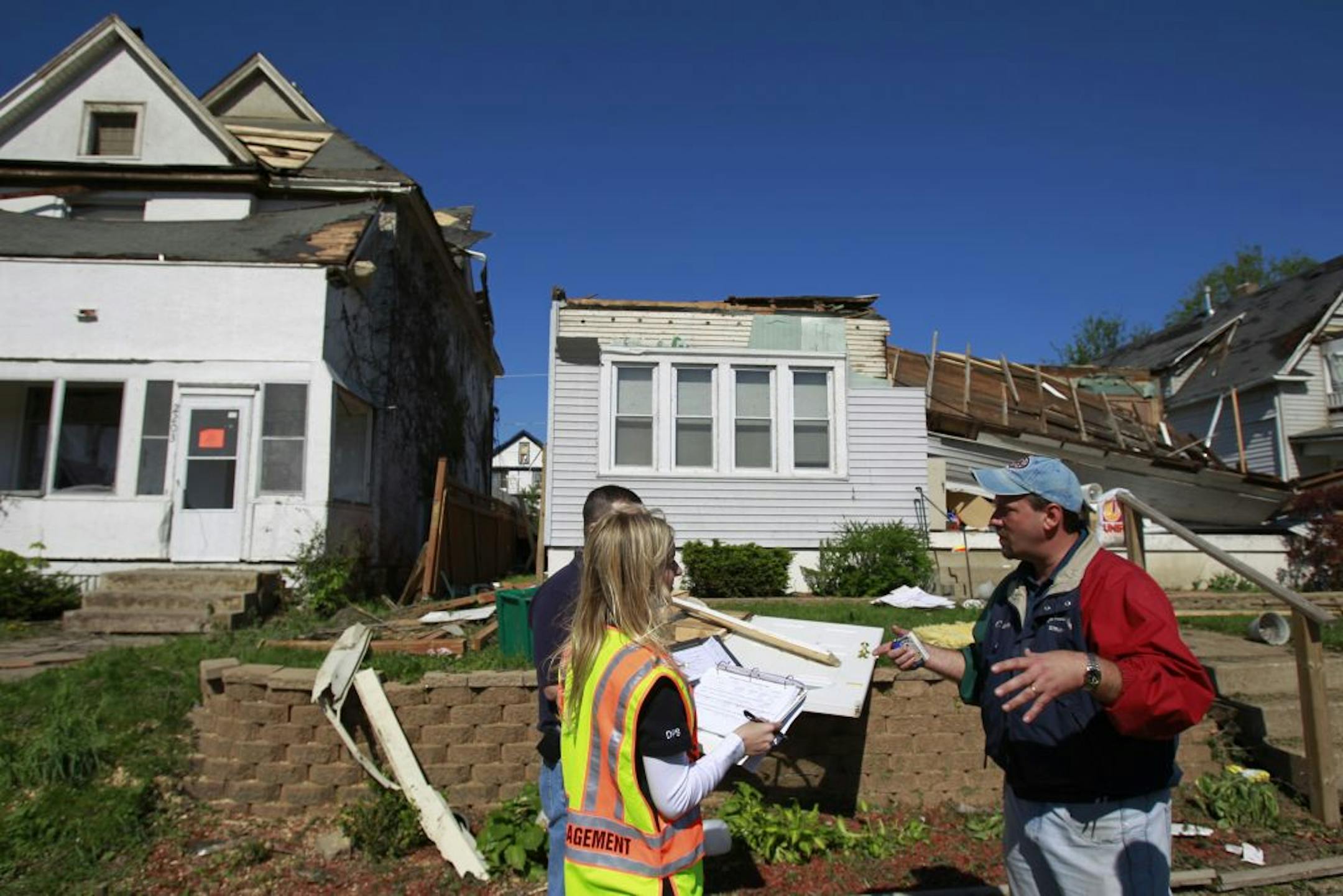 Homeowner Joshua Wickander, right, talked with FEMA official Scott Richardson left and Jenny Kane during an assessment of his home on the 2200 block of Queen Av. N.