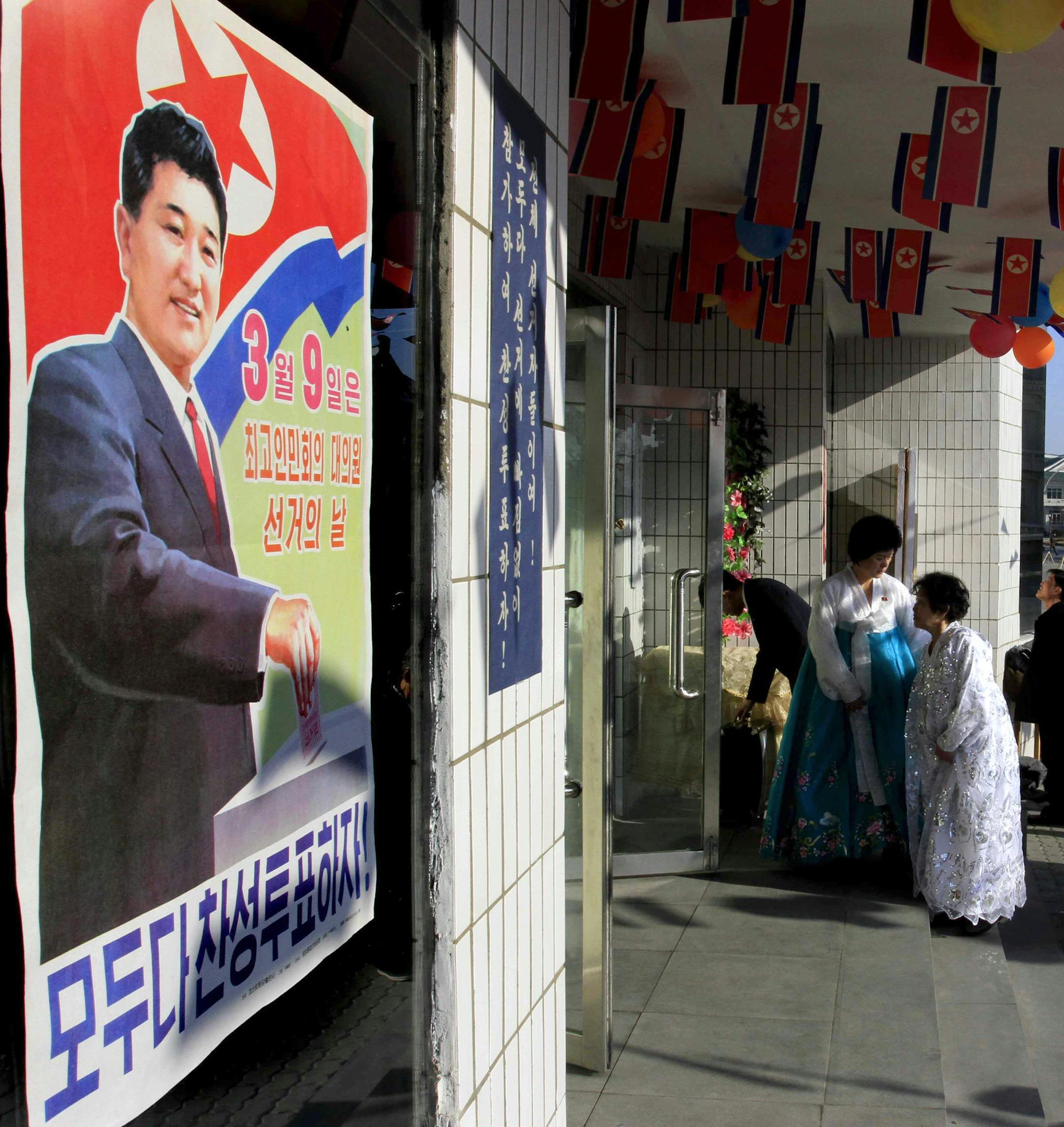 Voters line up to cast their ballots to elect deputies to the 13th Supreme People's Assembly in Pyongyang, North Korea Sunday, March 9, 2014. North Korean voters went to polling stations to elect a new national legislature, although they don't get to choose who to vote for since there is only one candidate per district. The sign at left reads "March 9 is the Supreme People’s Assembly’s Deputies Election Day," in red, and "Everyone, let’s give assenting votes! " in blue at bo