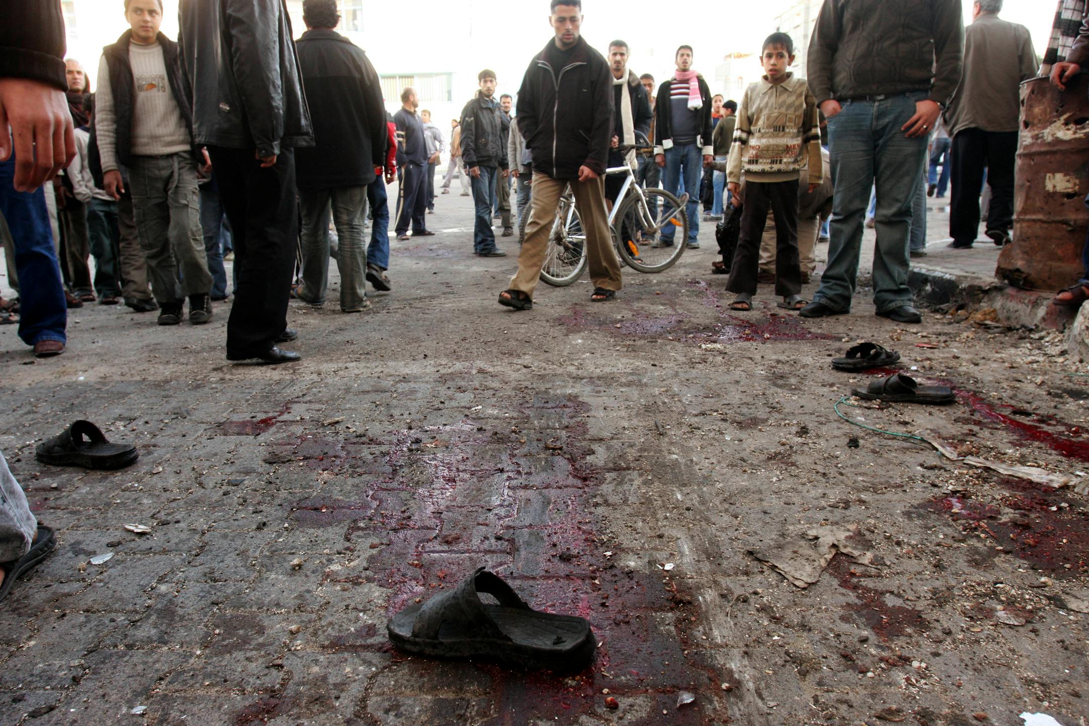 Palestinians gather at the site of an Israeli strike on a street near a U.N. school, after an Israeli attack killed dozens of Palestinians, in Jabaliya refugee camp, northern Gaza Strip, Tuesday, Jan. 6, 2009. An Israeli bombardment struck outside a U.N. school where hundreds of Palestinians had sought refuge on Tuesday, the U.N. and Palestinian medics said, killing at least 30 people, many of them children whose parents wailed in grief at a hospital filled with dead and wounded.