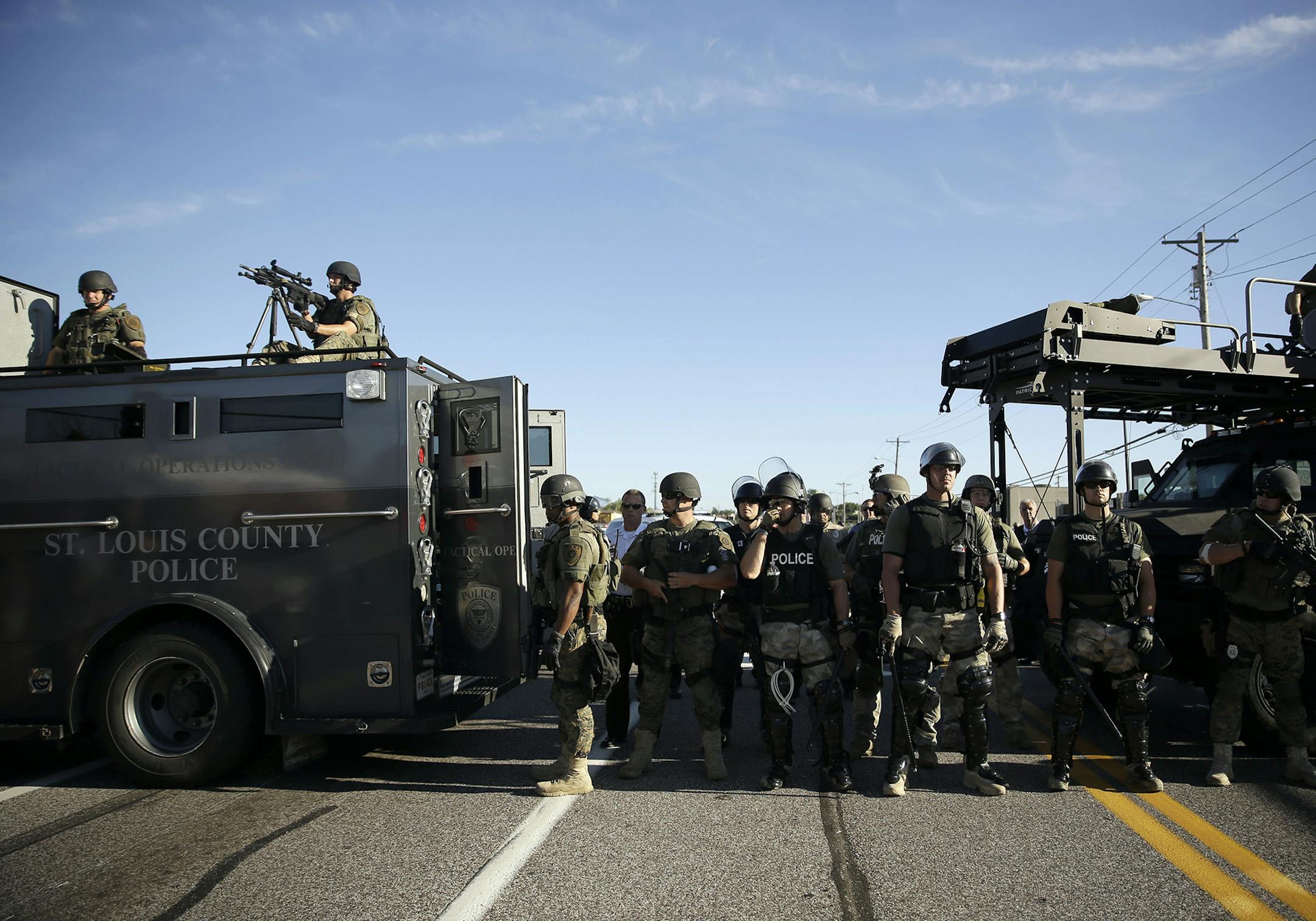 Police in riot gear watch protesters in Ferguson, Mo. on Wednesday, Aug. 13, 2014. On Saturday, Aug. 9, 2014, a white police officer fatally shot Michael Brown, an unarmed black teenager, in the St. Louis suburb. (AP Photo/Jeff Roberson) ORG XMIT: MIN2014081812294932