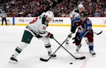 Minnesota Wild center Luke Kunin, left, reaches for the puck as Colorado Avalanche left wing Gabriel Bourque defends during the third period of an NHL