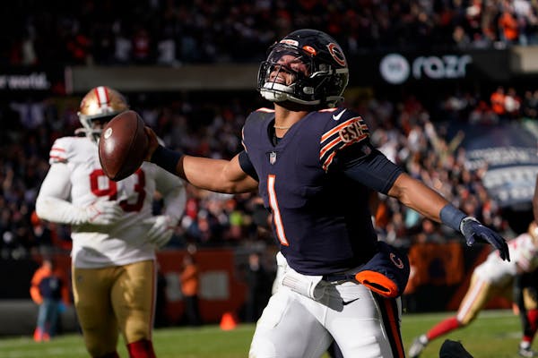 Chicago Bears quarterback Justin Fields begins to celebrate his touchdown against the San Francisco 49ers during the second half of an NFL football ga