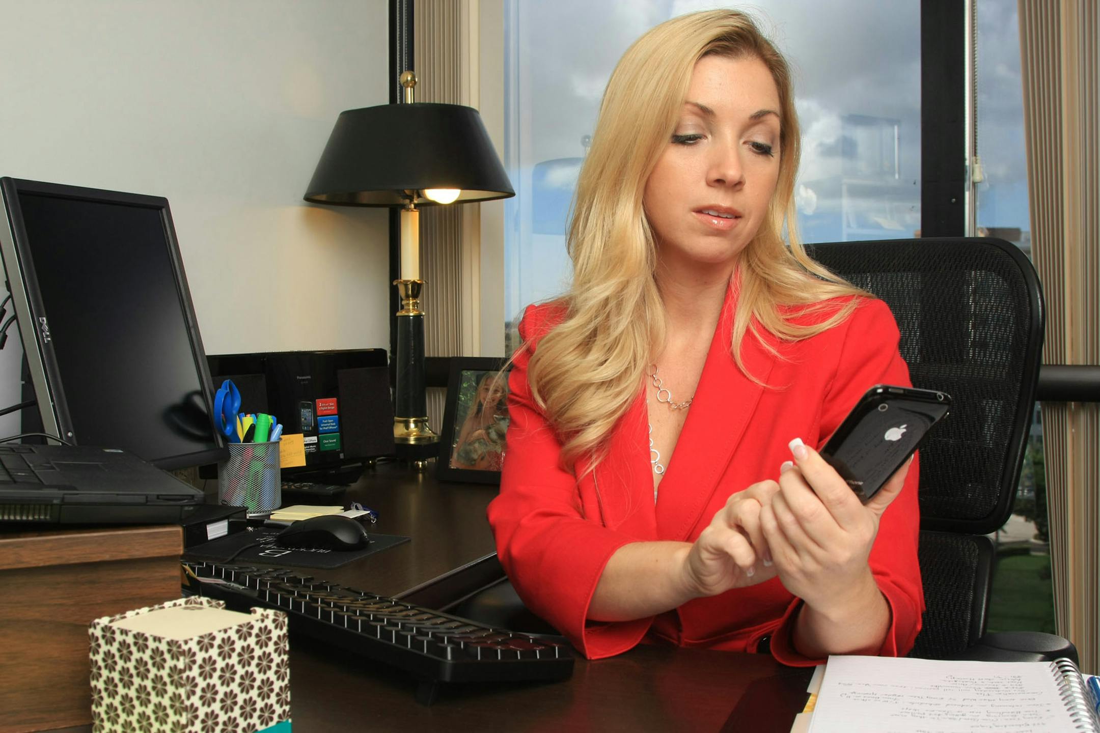 While at work, single mom Eden Rose, an office administrator at the law offices of Buckingham Doolittle & Burroughs, LLP, uses her iPhone to monitor her daughter, locating her through Google Latitude and communicating through texting, August 23, 2011, in Boca Raton, Florida. For most Americans, 2011 was the year of overwork or underwork. (Tom Ervin/Miami Herald/MCT)