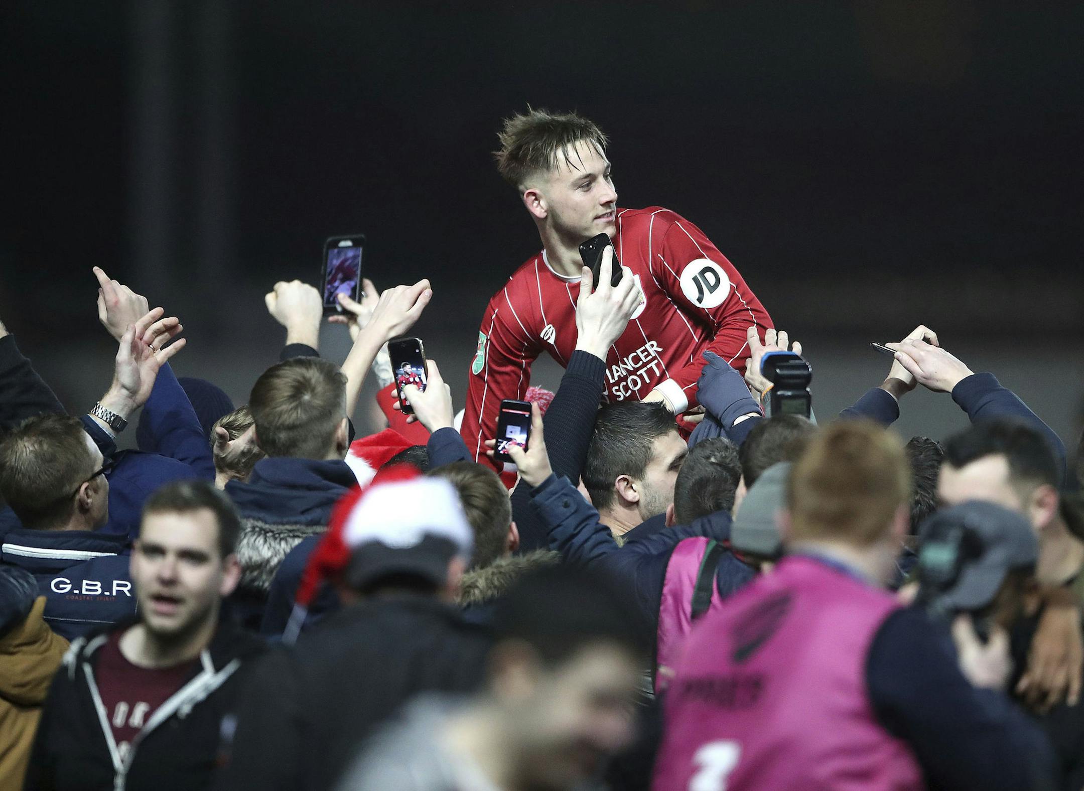 Bristol City's Josh Brownhill celebrates their victory as he is lifted up by fans after the final whistle in the English League Cup Quarter Final soccer match between Bristol City and Manchester United at Ashton Gate, Bristol, England, Wednesday, Dec. 20, 2017. Bristol City defeated Manchester United 2-1. (Nick Potts/PA via AP)