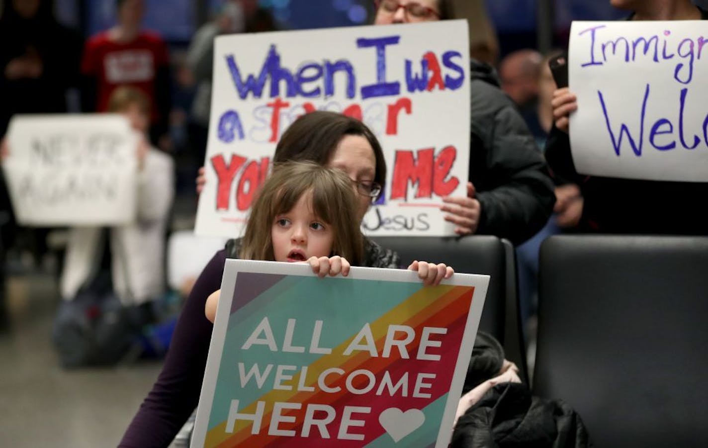 Rachel Walker of St. Paul and her daughter Evelyn, 7, share a message saying "All are welcome here" at MSP on Saturday.