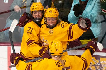 Gophers forward Emily Oden (21) and wing Peyton Hemp (15) celebrate with forward Addie Burton (26) after she scored a goal on Jan. 22