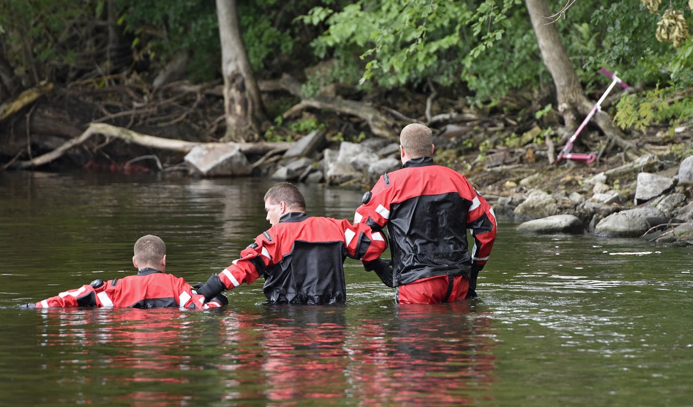 Sheriff's department dive team members join arms while conducting a search for 6-year-old Hamza Elmi Friday, July 24, 2015, near the location where his scooter was found on the banks of the Mississippi River in St. Cloud, Minn. His body was recovered in the river Friday. (Dave Schwarz /St. Cloud Times via AP) NO SALES; MANDATORY CREDIT