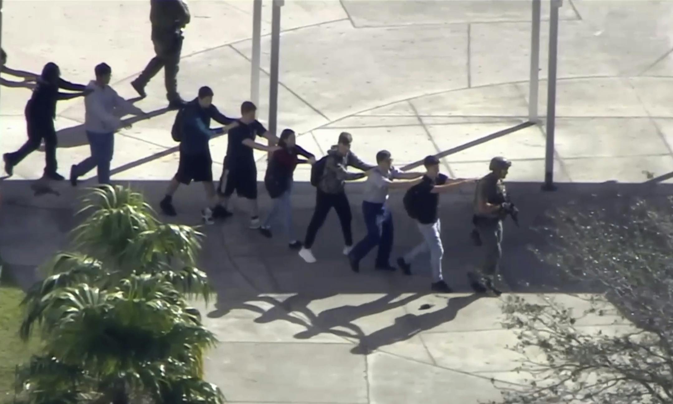 In this frame grab from video provided by WPLG-TV, students from the Marjory Stoneman Douglas High School in Parkland, Fla., evacuate the school following a shooting, Wednesday, Feb. 14, 2018. (WPLG-TV via AP)