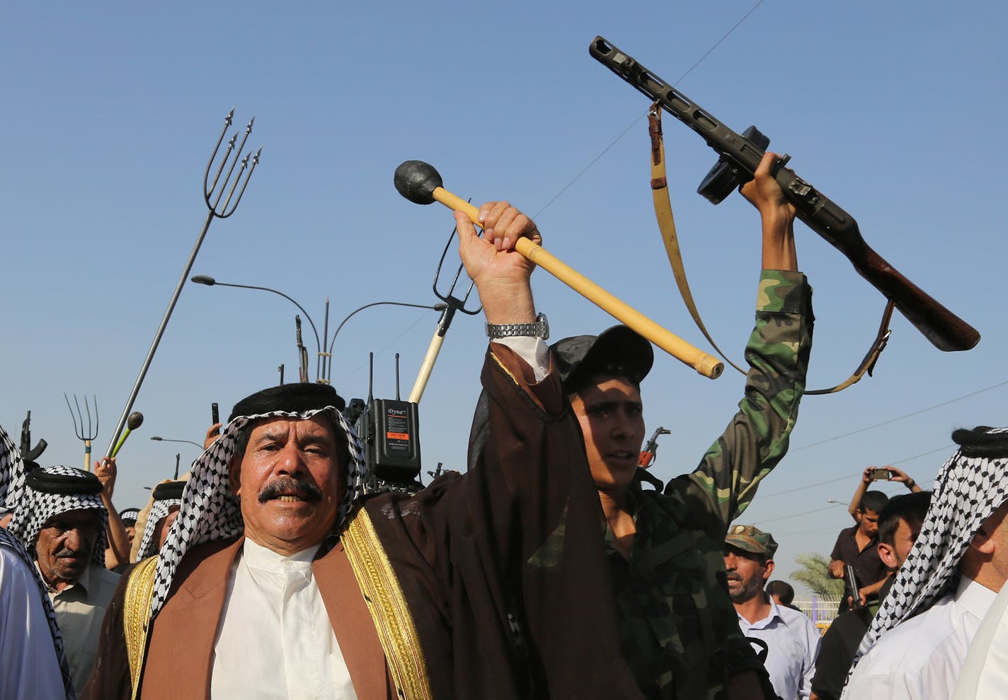 Shiite tribal fighters raise their weapons and chant slogans against the al-Qaida-inspired Islamic State of Iraq and the Levant (ISIL) in the northwest Baghdad's Shula neighborhood, Iraq, Monday, June 16, 2014. Sunni militants captured a key northern Iraqi town along the highway to Syria early on Monday, compounding the woes of Iraq's Shiite-led government a week after it lost a vast swath of territory to the insurgents in the country's north. (AP Photo/ Karim Kadim) ORG XMIT: MIN201406171414565