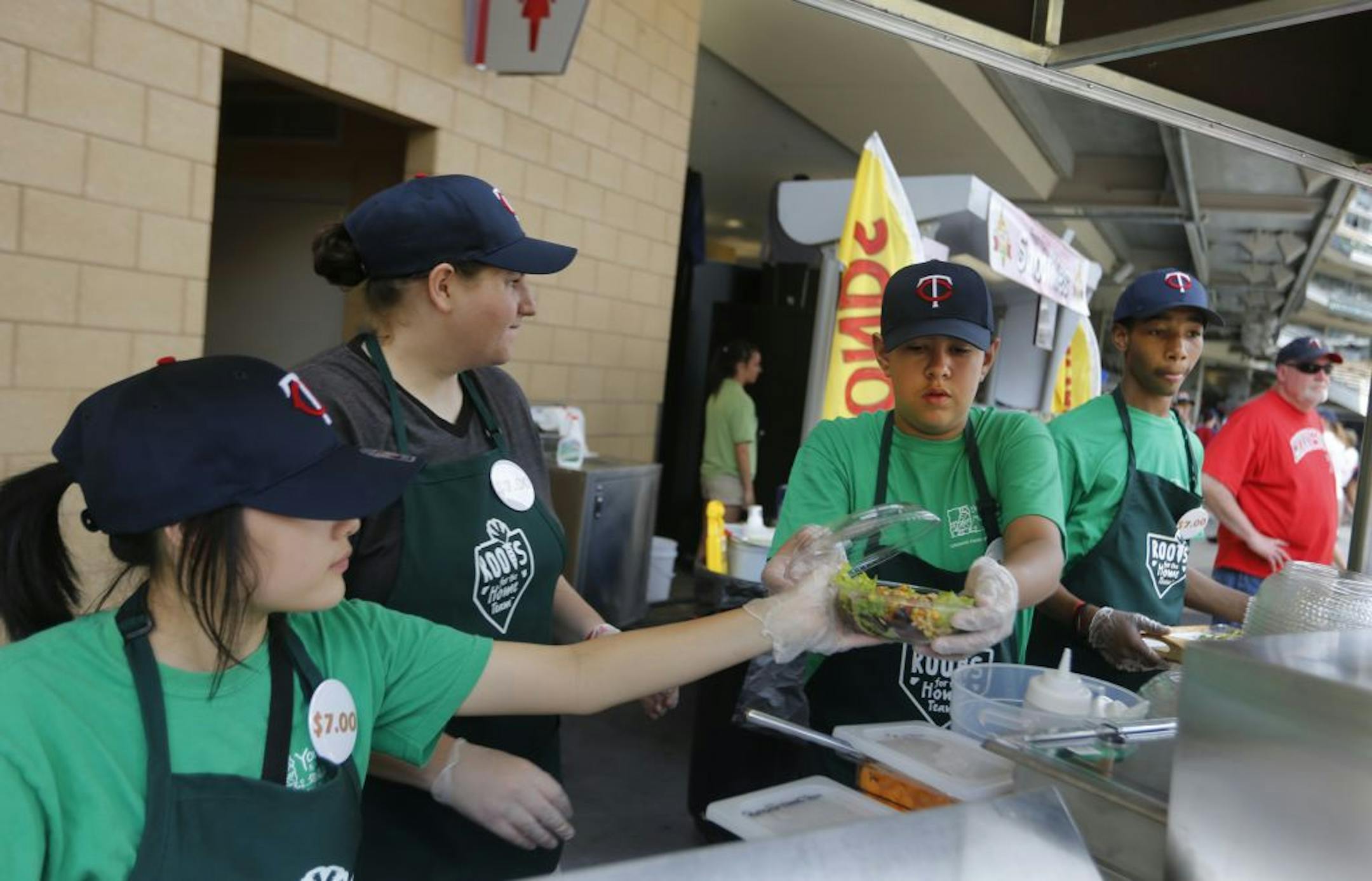 At Target Field at the Garden Goodies cart, left to right, Kabao Lee, mentor Monica McDaniel, Sergio Arredondo, and Teshaun Wade helped serve their locally grown salads .