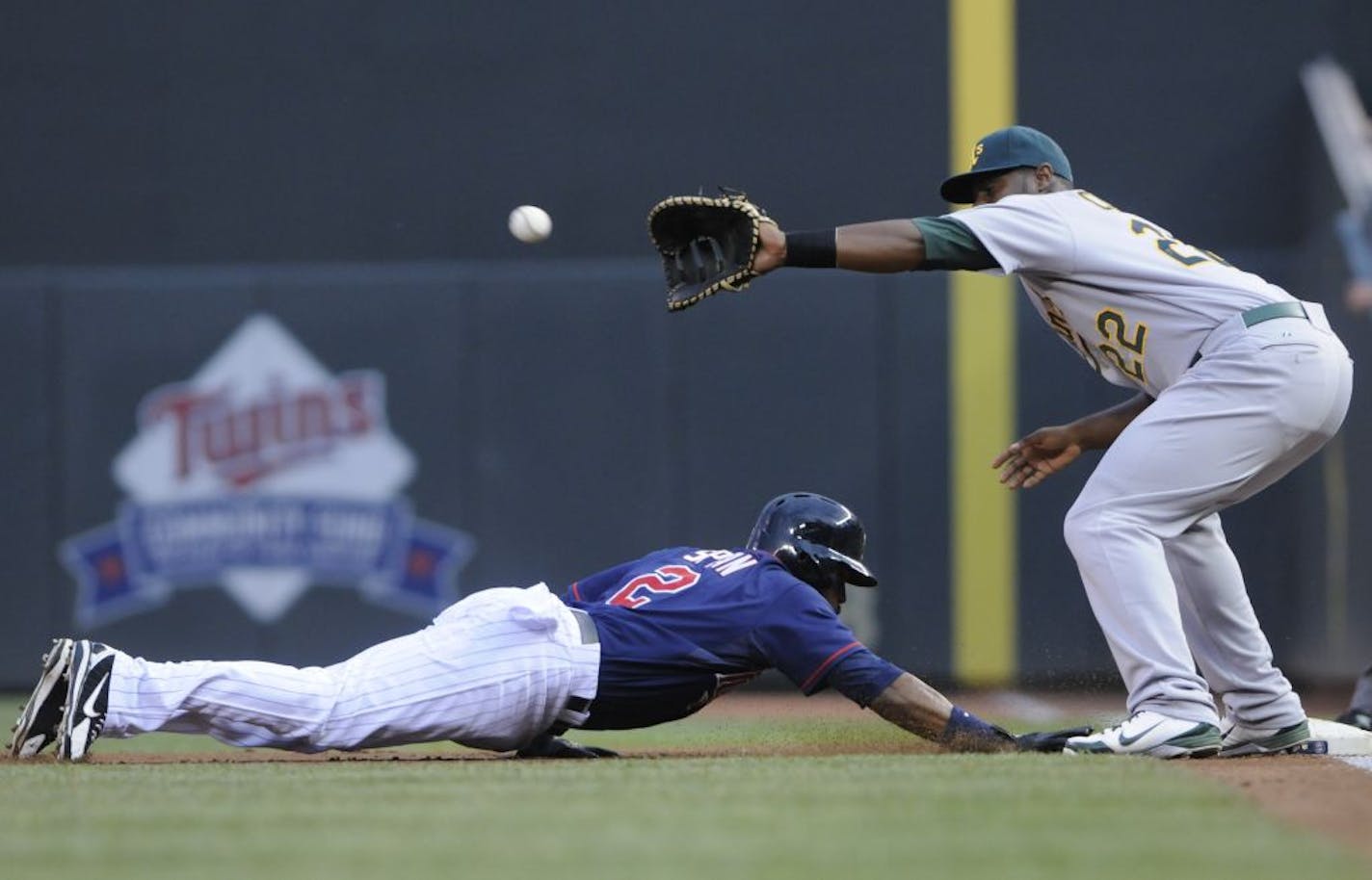 Oakland Athletics' Chris Carter, right, awaits the throw as Minnesota Twins' Denard Span dives safely back to first on a pick-off attempt in the first inning of a baseball game Friday, July 13, 2012, in Minneapolis.