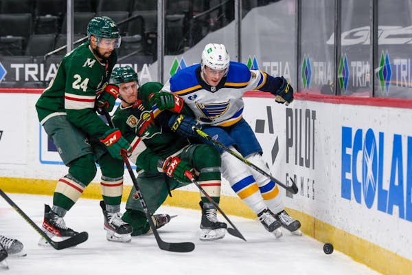 Minnesota Wild defenseman Matt Dumba (24) and center Nico Sturm, center, and St. Louis Blues center Ryan O'Reilly try to control the puck during the s