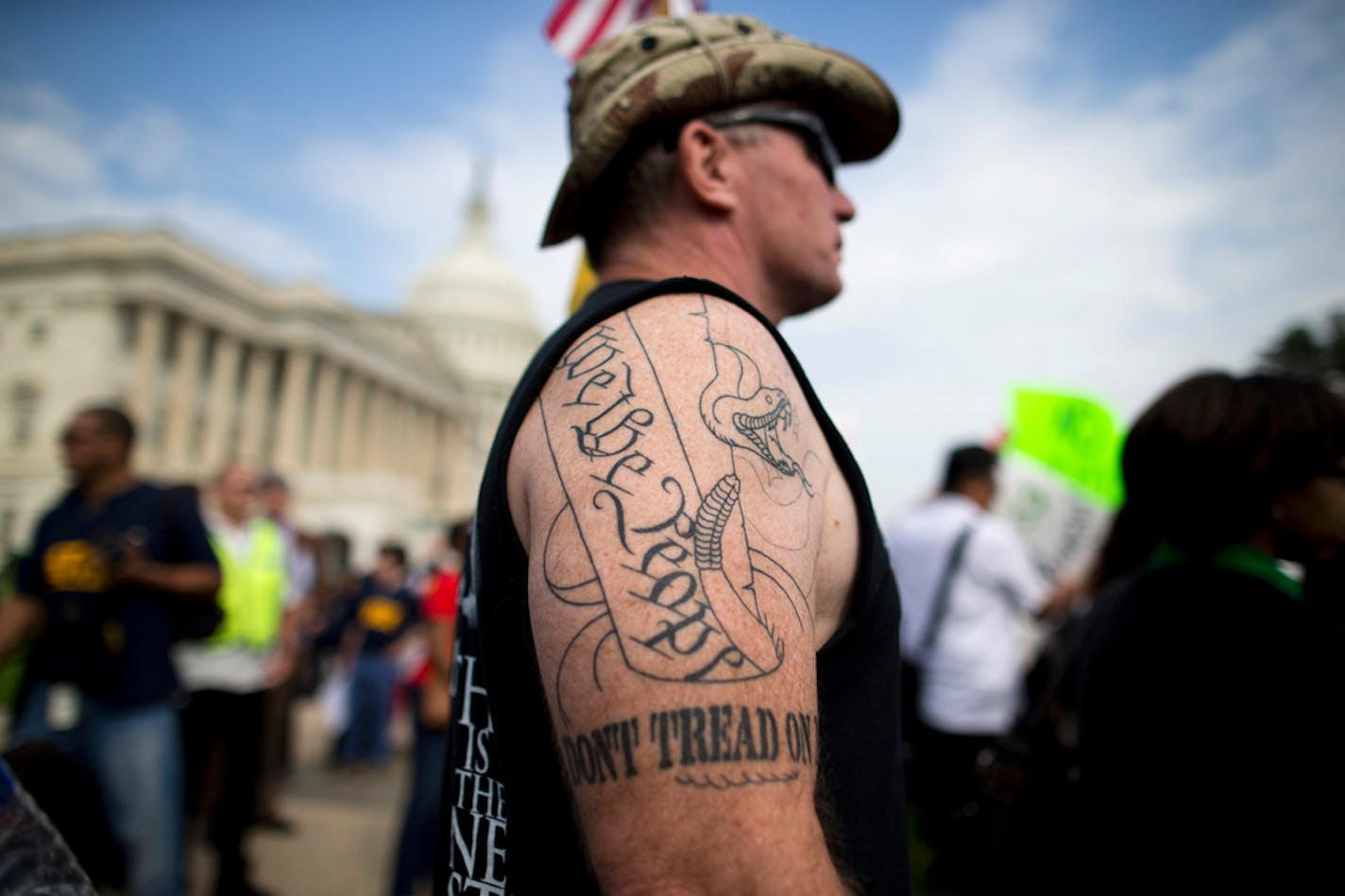 Tea Party supporter Greg Cummings of Cincinnati, Ohio, watches a rally with the Democratic Progressive Caucus and furloughed federal employees against House Republicans on Capitol Hill in Washington, Friday, Oct. 4, 2013. Cummings attended the rally to blame Senate Democrats for the government shutdown. (AP Photo/ Evan Vucci)