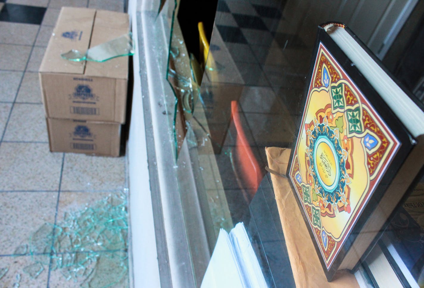 A copy of the Quran is shown above the shattered glass from a broken window at a south Minneapolis mosque.