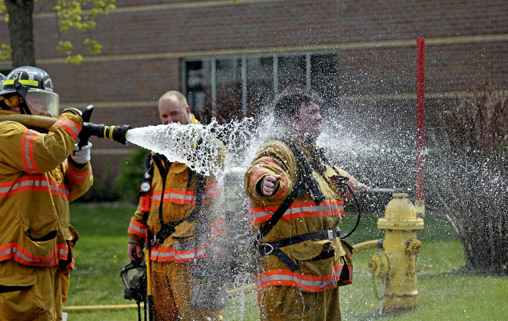 A firefighter who had been inside the building is decontaminated with water.