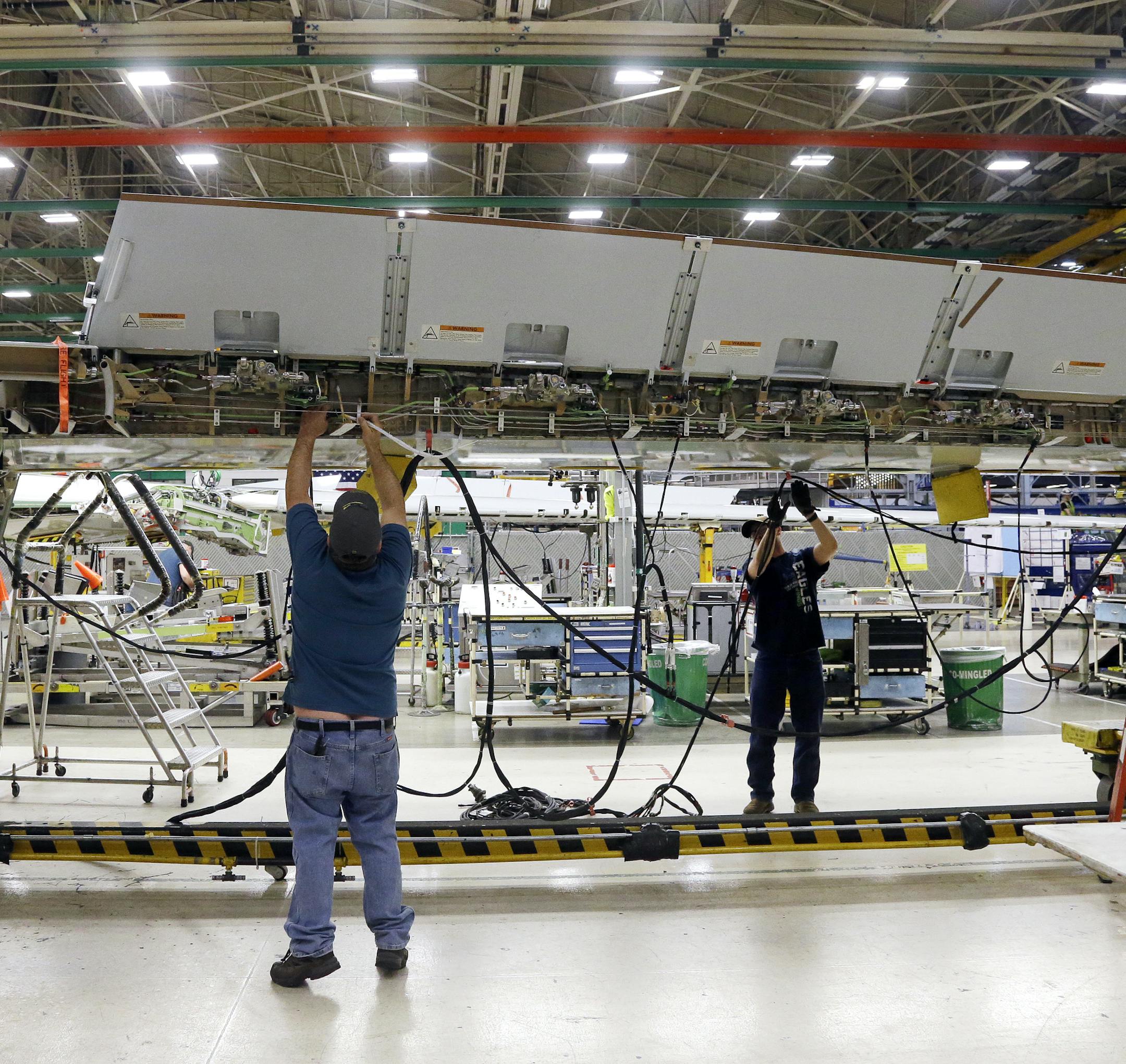 Workers assembly a Boeing's 737 MAX airplane wing at the company's production facility Monday, Feb. 13, 2017, in Renton, Wash. Boeing plans to deliver its first 737 MAX airplane by May. Boeing's latest innovations inside its Renton factory includes new robotic machines as well as more efficient ways of deploying its mechanics. The company is also increasing its 737 production rate to 47 per month, from 42. (AP Photo/Elaine Thompson)