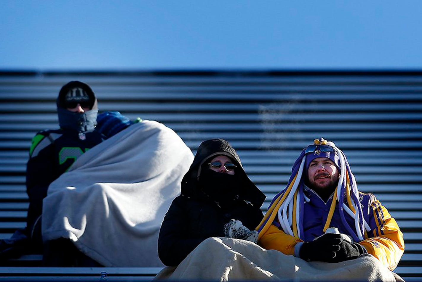 Seattle Seahawks and Minnesota Vikings fans watch team warm-ups with blankets in the stands.