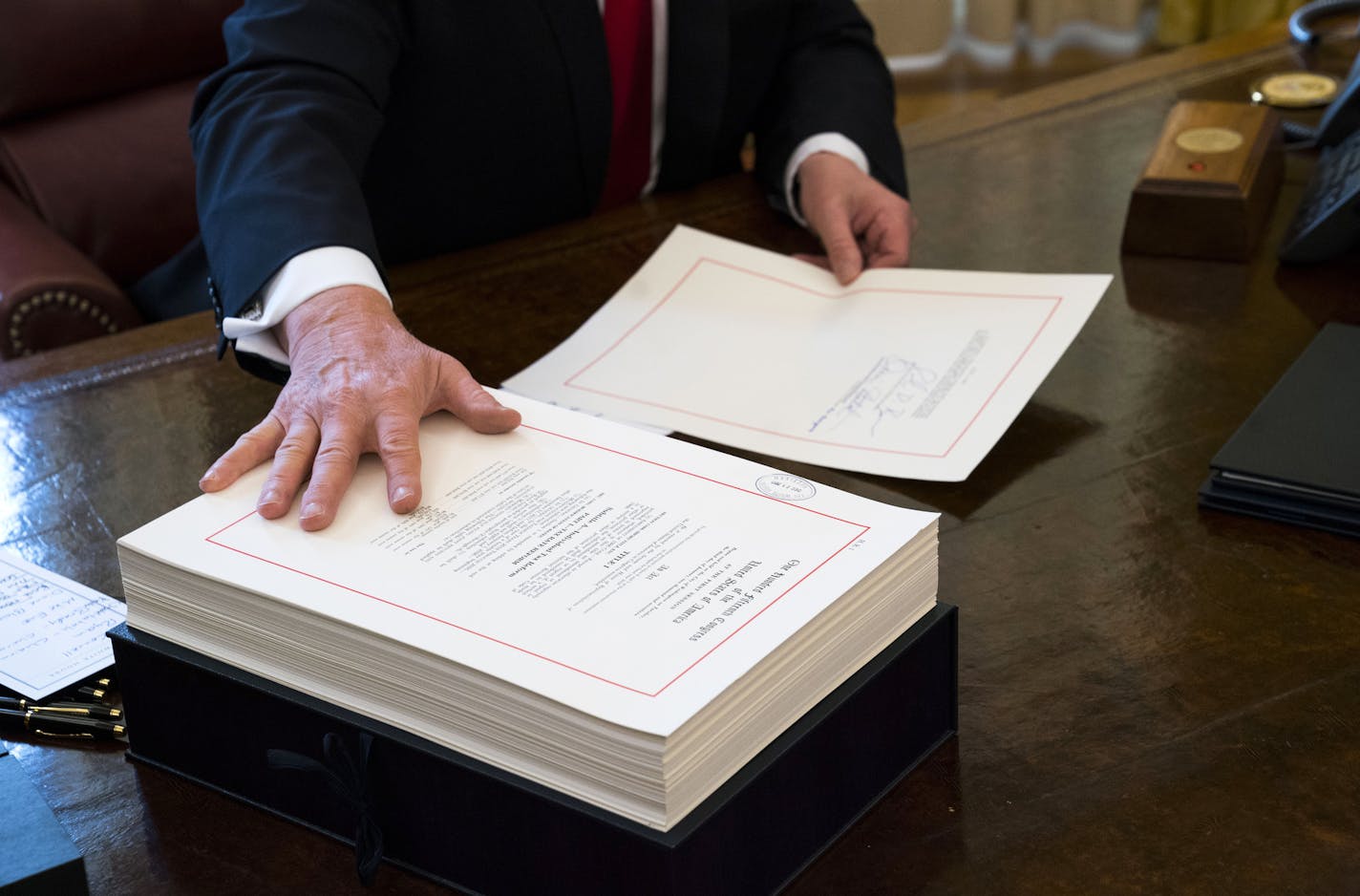 FILE -- President Donald Trump signs the tax reform bill in the Oval Office of the White House in Washington, Dec. 22, 2017. Nearly a year after the tax cut, economic growth has accelerated, wage growth has not. Companies are buying back stock and business investment is a mixed bag. (Doug Mills/The New York Times)