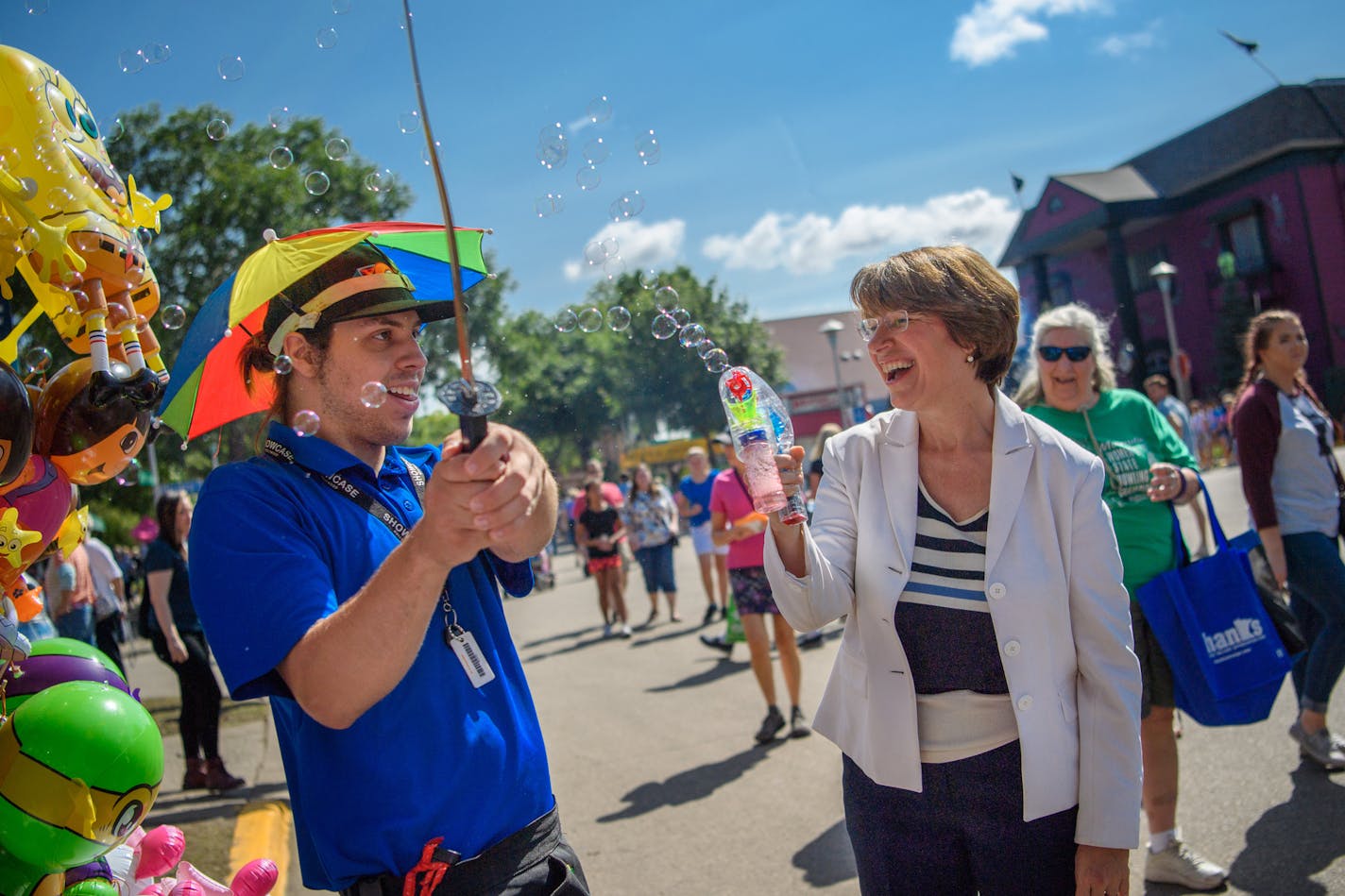 Nick Craton of Dandy Souvenir showed Sen. Amy Klobuchar how to use his bubble gun then chopped at the bubbles with his plastic sword at the Minnesota State Fair.