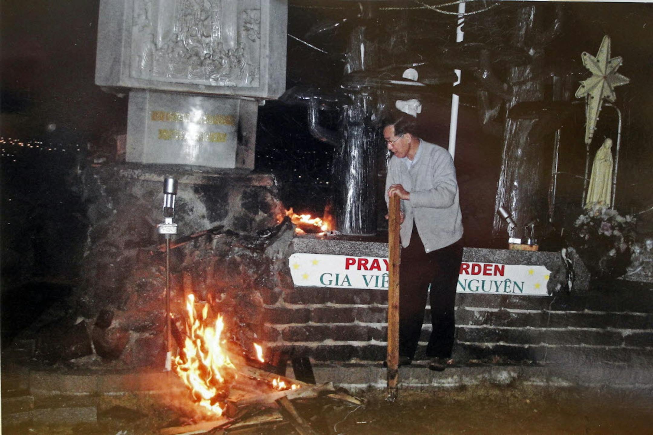 Tuan Pham attempts to extinguish the fire set at the base of the statue early Sunday morning.