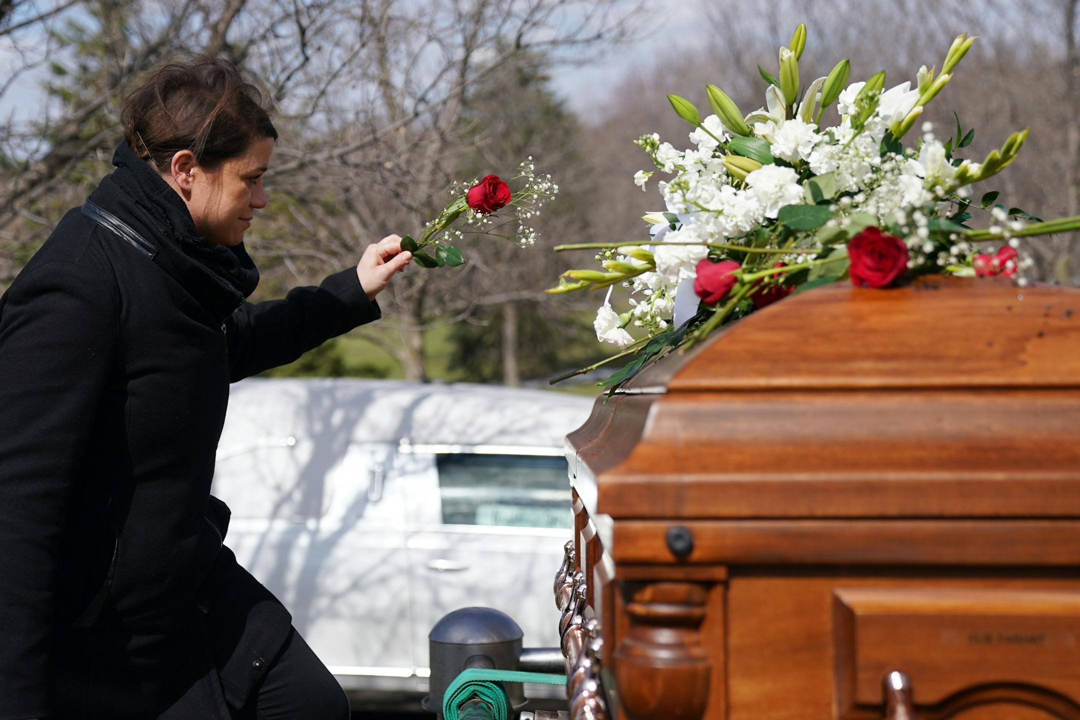 Elianne Farhat placed a rose on the casket of her grandfather Elie Farhat, who recently died of COVID-19 at the age of 92, following funeral services at his gravesite Thursday.