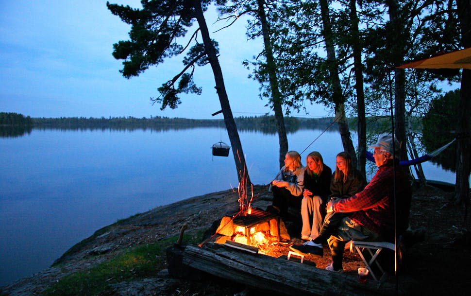 Sarah Ozment, Alyssa Chandler, Natalie Peterson with around the Campfire at Lake Three in the BWCA with their grandfather Ken Johnson.