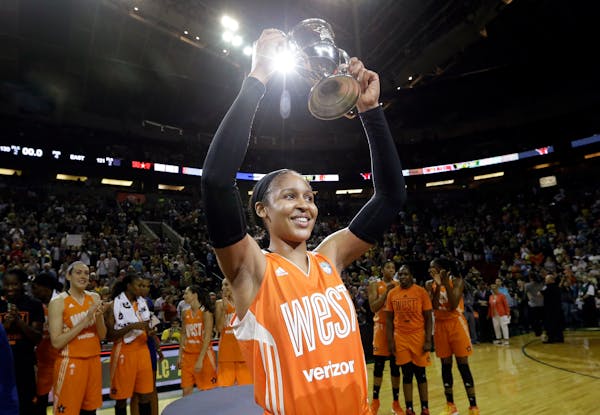 Minnesota Lynx's Maya Moore, of the Western Conference, holds up a trophy after being named most valuable player as teammates cheer behind after the W