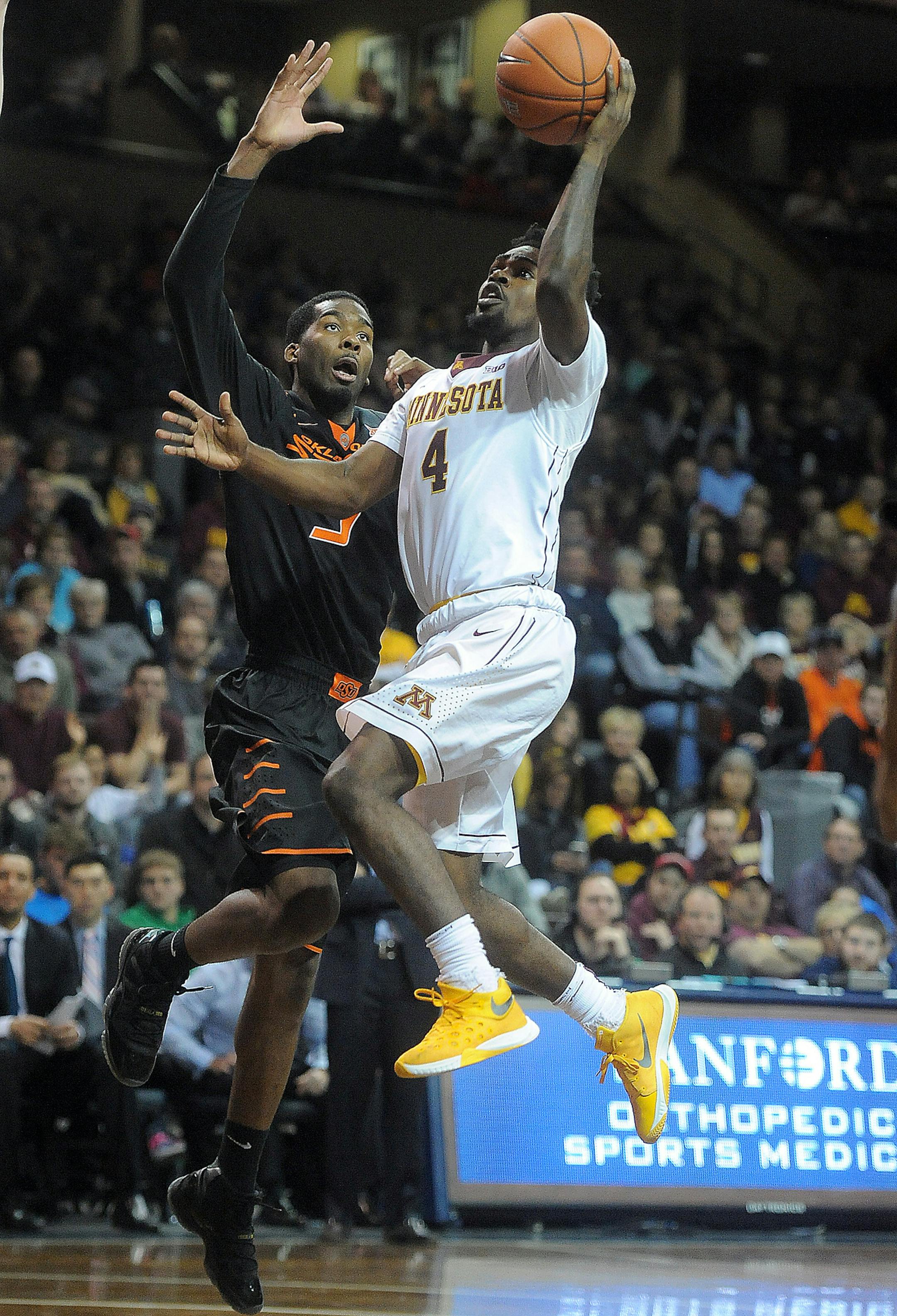 Minnesota's Kevin Dorsey (4) goes up for a shot over Oklahoma State's Tavarius Shine (5) during their game at the Sanford Pentagon in Sioux Falls, S.D. on Saturday, Dec. 12, 2015. (Jay Pickthorn/The Argus Leader via AP)